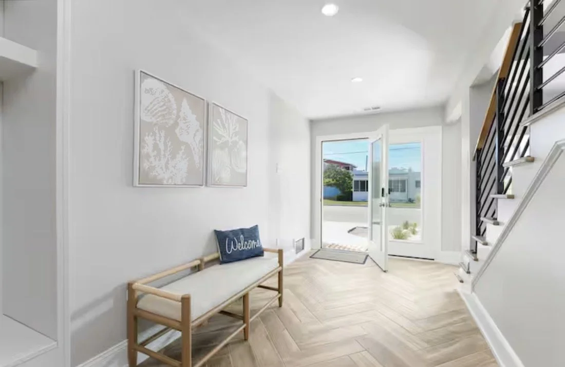 This bright coastal entryway in Kure Beach was designed to create a warm and welcoming first impression, featuring natural wood flooring, soft neutral tones, and clean timeless finishes inspired by relaxed seaside living.