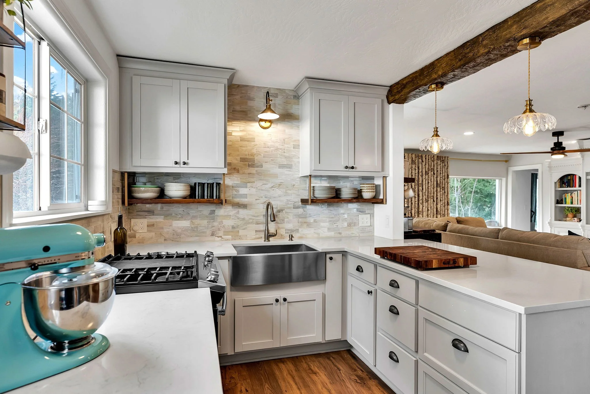 Custom cottage kitchen design in Bayview Idaho with white shaker cabinets, farmhouse sink, quartz countertops, and rustic wood beam.