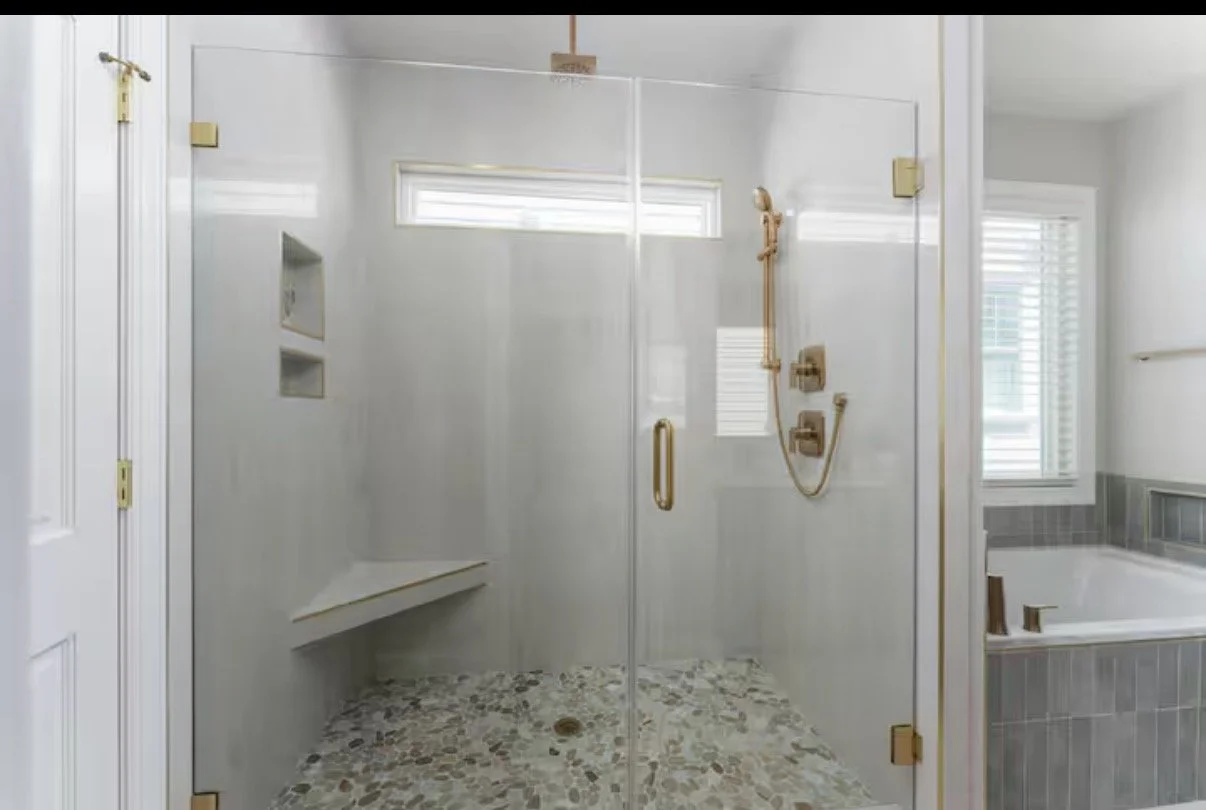 Custom walk-in shower featuring timeless marble-look tile, brass fixtures, and clean coastal finishes designed for both luxury and durability in this Kure Beach vacation rental.