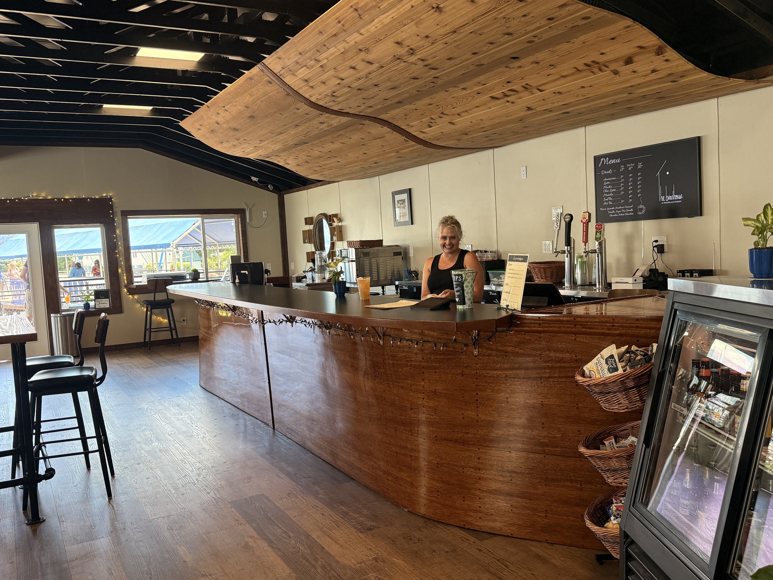 The custom curved bar creates a focal point in this Bayview café, combining handcrafted woodwork with functional hospitality design for a warm and approachable customer experience.