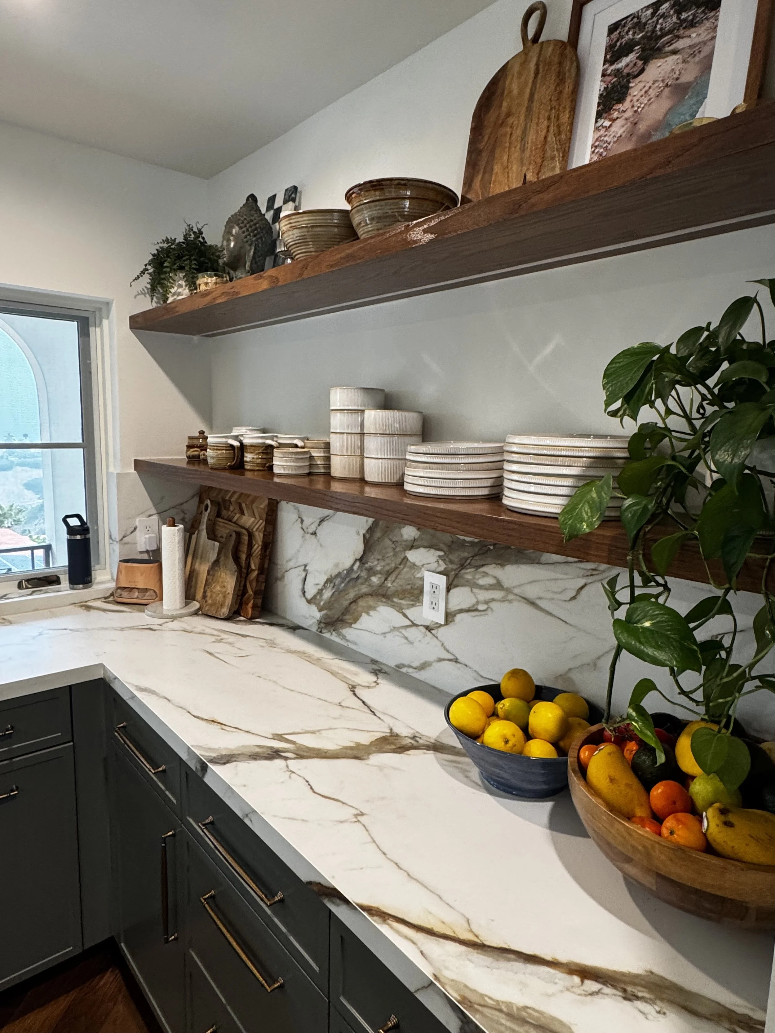 High-end kitchen design with custom cabinetry, waterfall marble island, artisan plaster range hood, brass fixtures, and natural wood details. A timeless, collected interior designed for warmth, beauty, and everyday function.