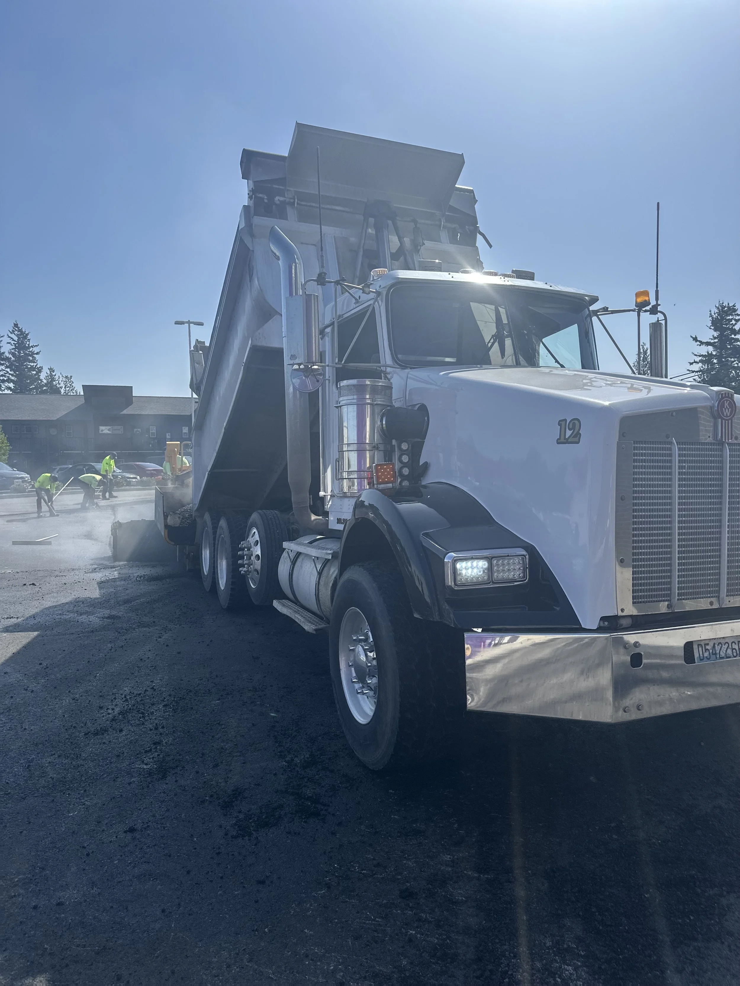 Construction workers smoothing asphalt on tractor supply parking lot in Lynden WA. sovereign trucking