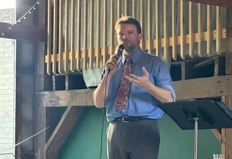 Sean Steeg holding a microphone, speaking to a group