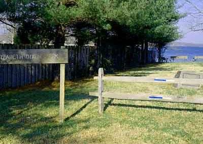 Elizabeth Dixon park with a wooden fence, trees, and a view of the water in the background.