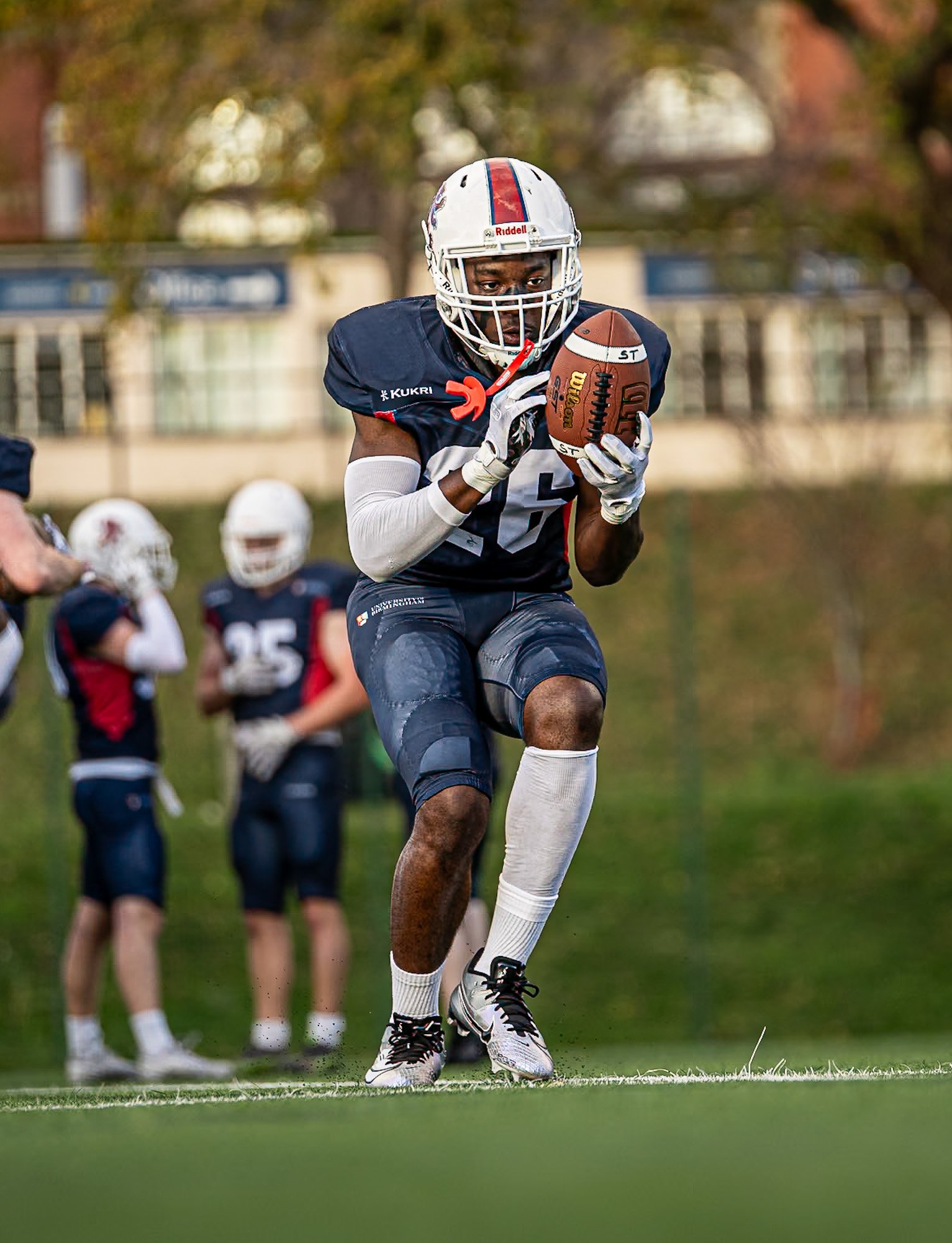 american football player carrying a ball