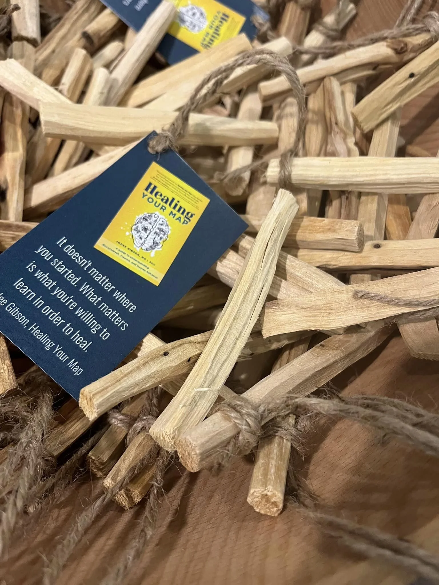 A pile of small wooden sticks with a blue tag attached reading 'Healing Your Map' and a quote about healing.