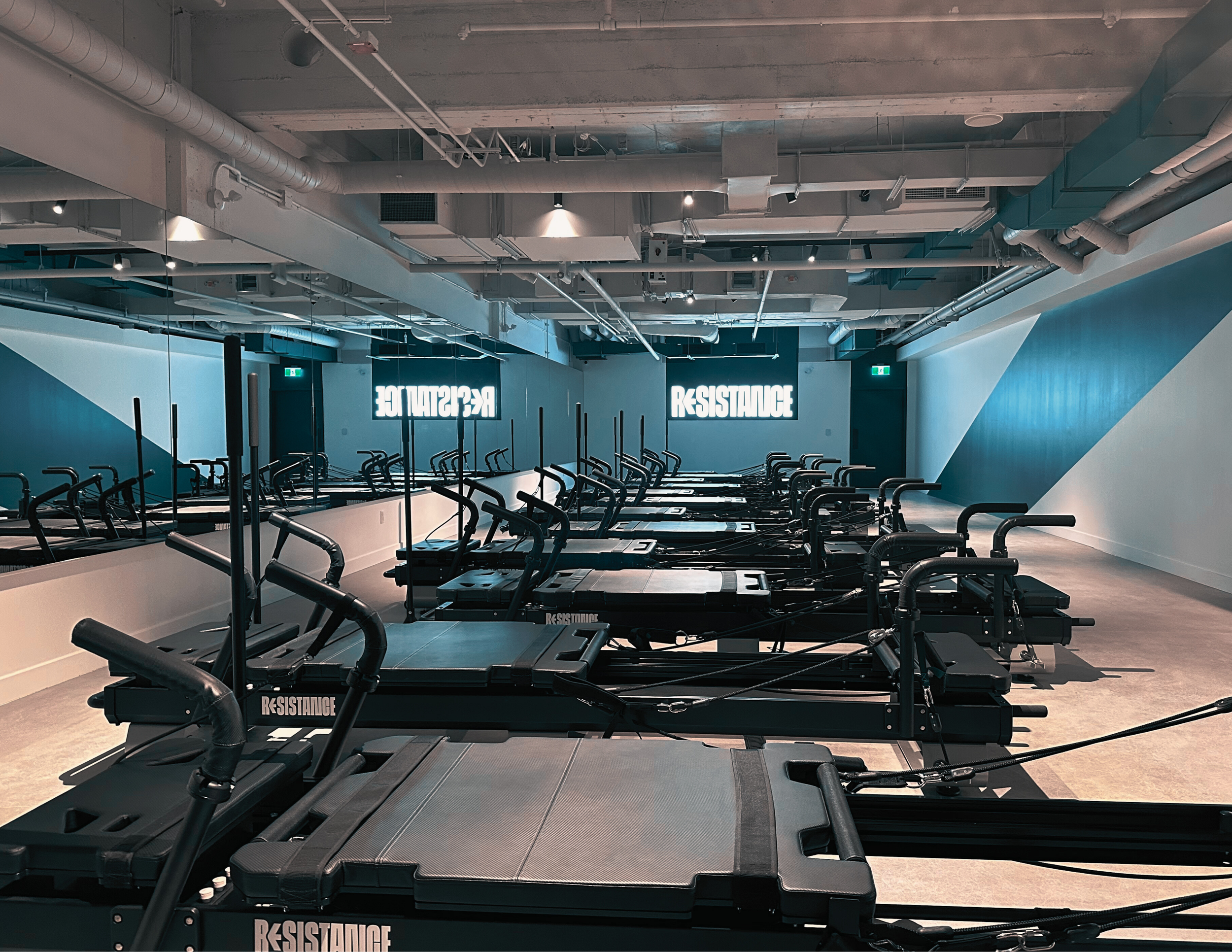 A large green circular sculpture in the middle of a city street between tall office buildings, with a mountain and cloudy sky in the background.
