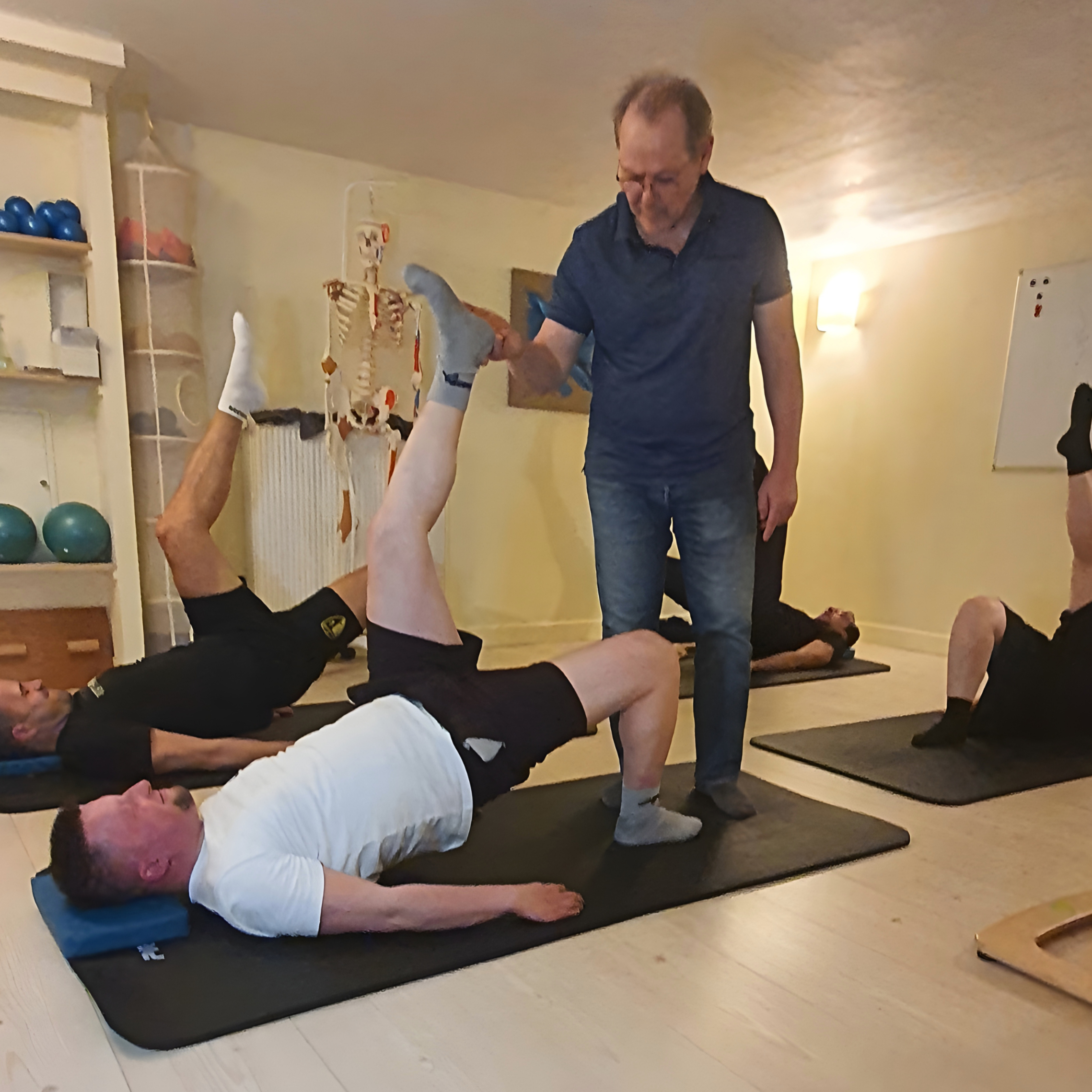 Xavier, enseignant à une séance de Pilates de Pilates, avec d'autres personnes en position allongée.