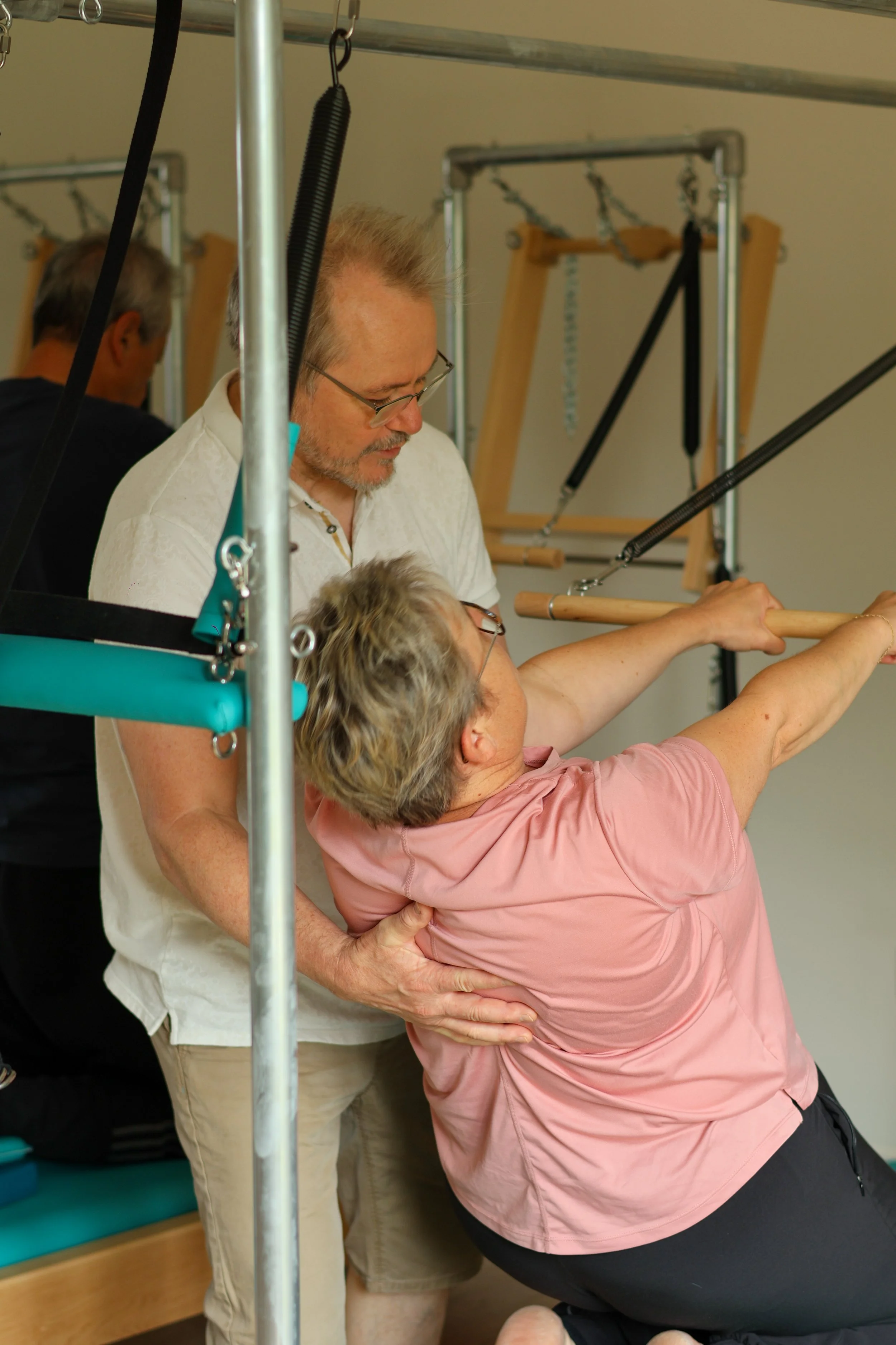 enseignant en pilates accompagnant son eleve dans exercice sur reformer 