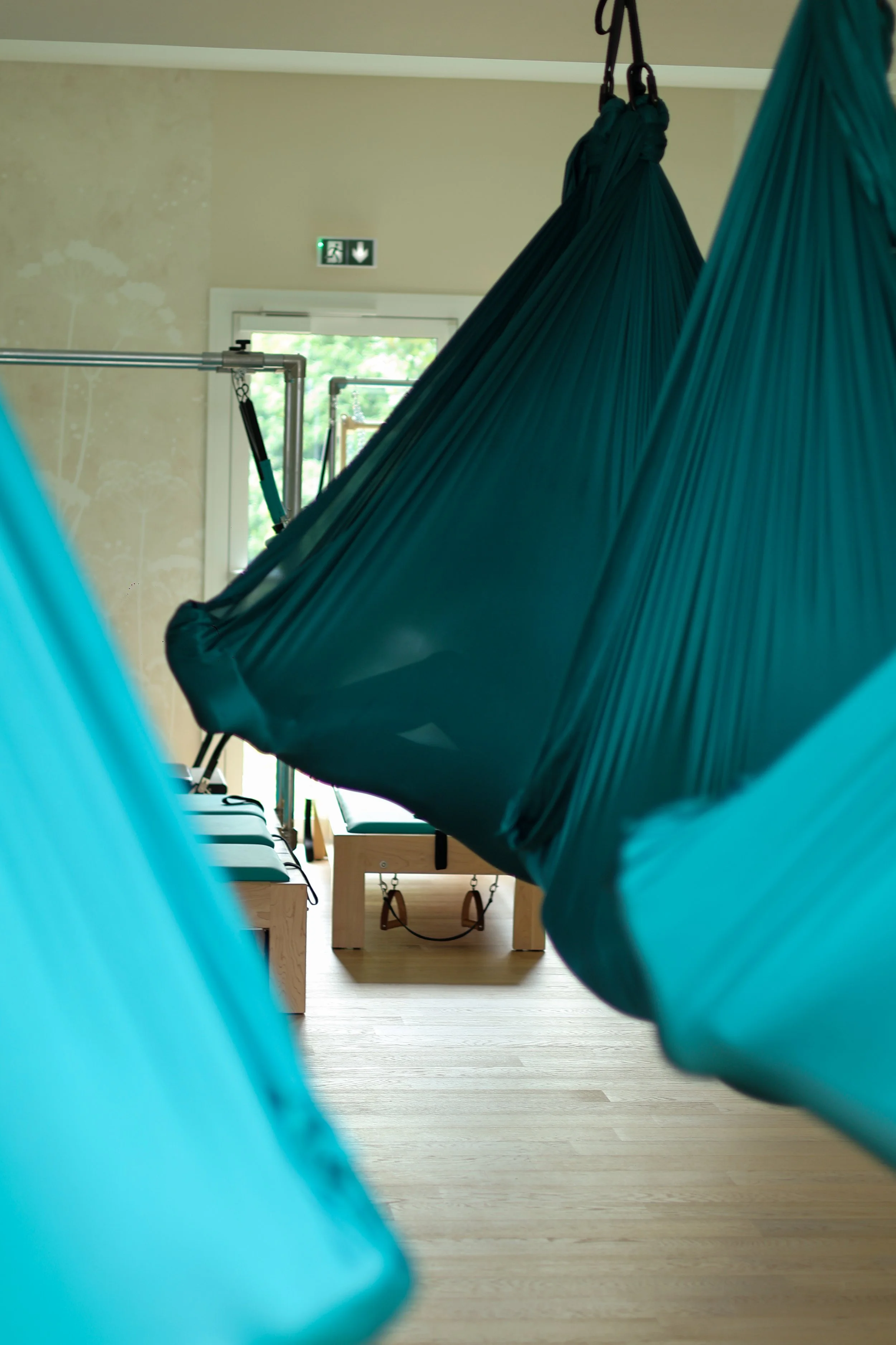 dans un studio de pratique pilates et yoga aerien 4 personnes sont allongees dans hamac 