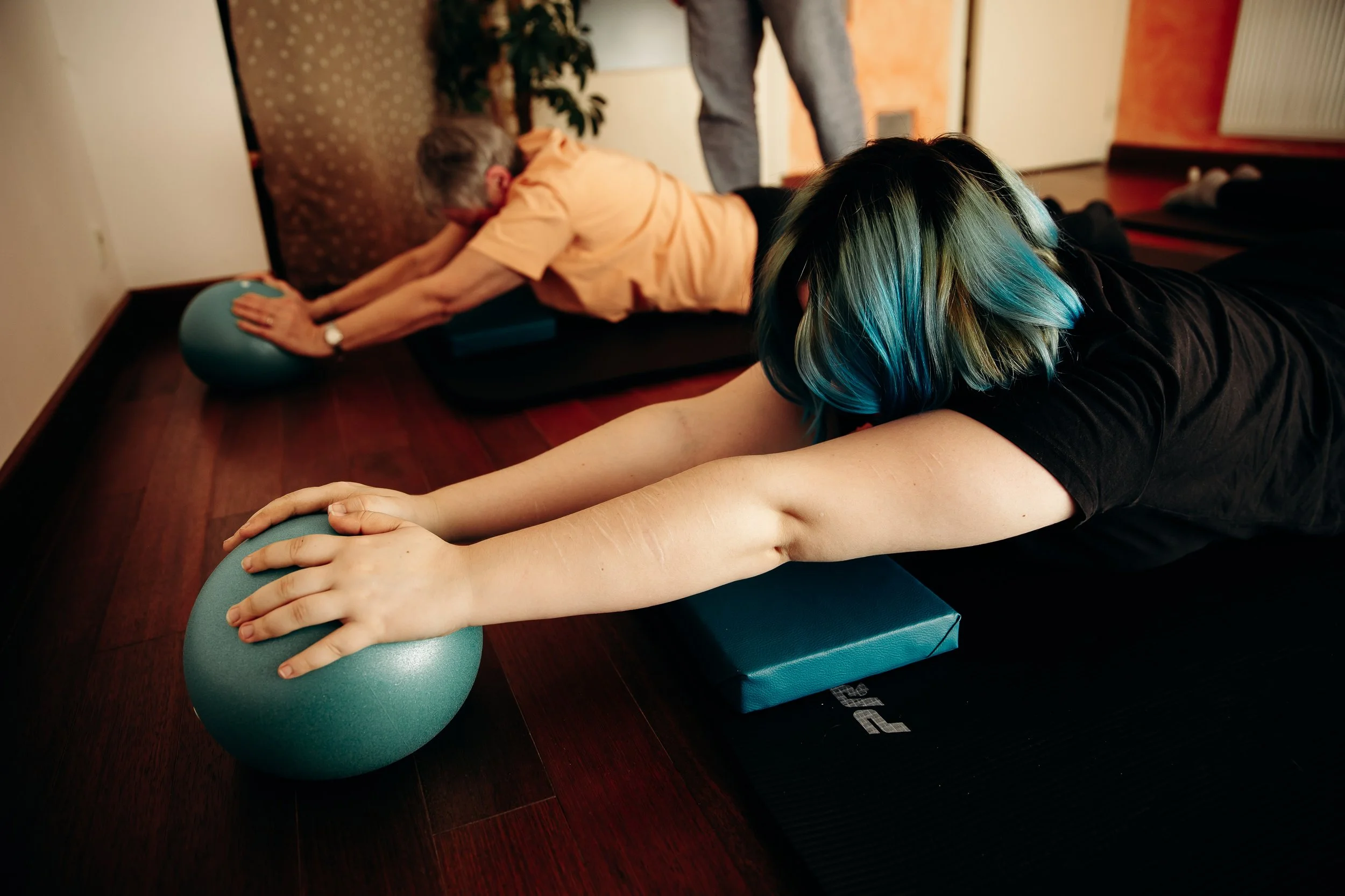 Deux personnes faisant de l'exercice de stretching sur des tapis de yoga, en utilisant des ballons d'exercice dans une pièce chaleureuse.