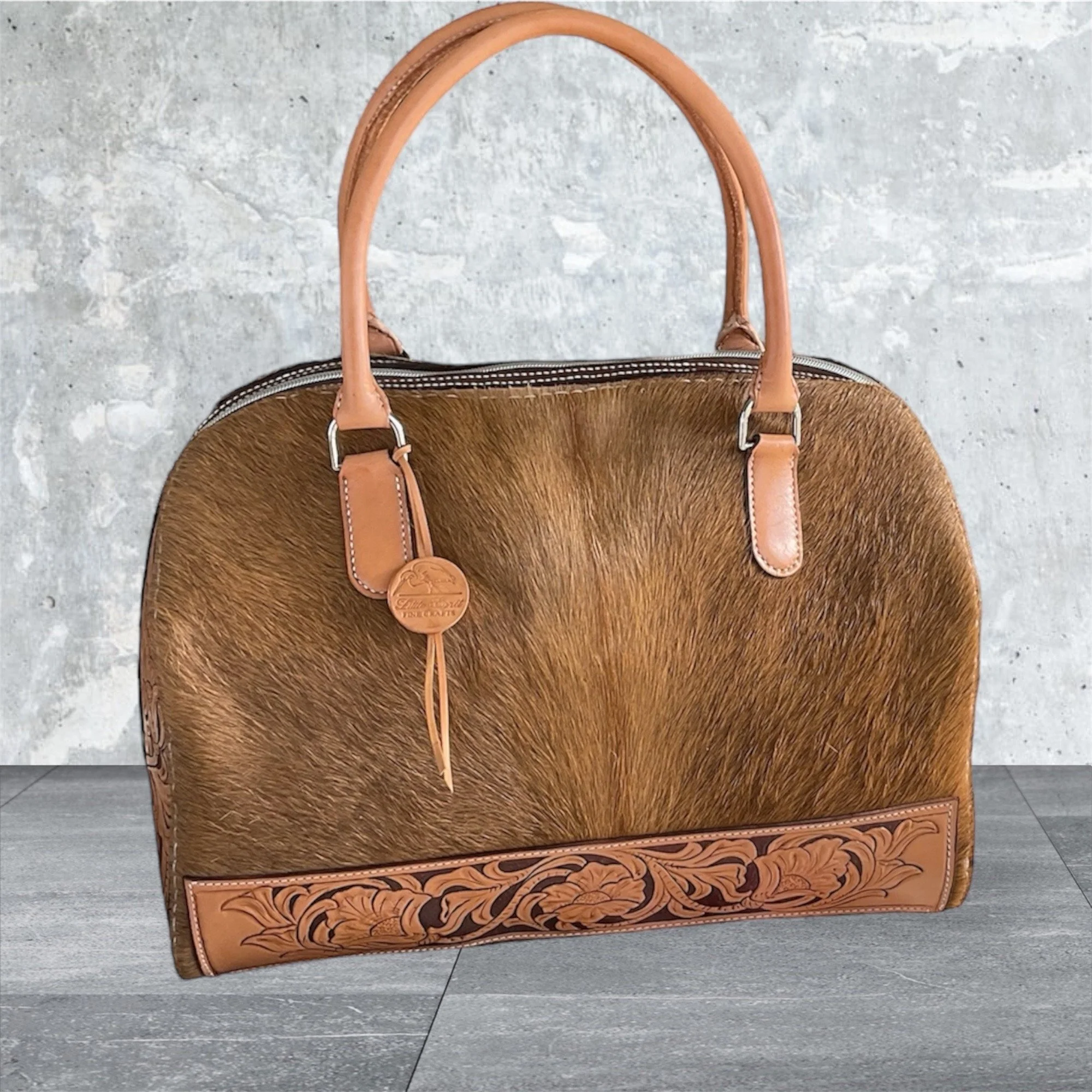 A hand carved and hand stitched duffle bag with hair-on cowhide.  I was quite proud of my Sheridan style carving design. 