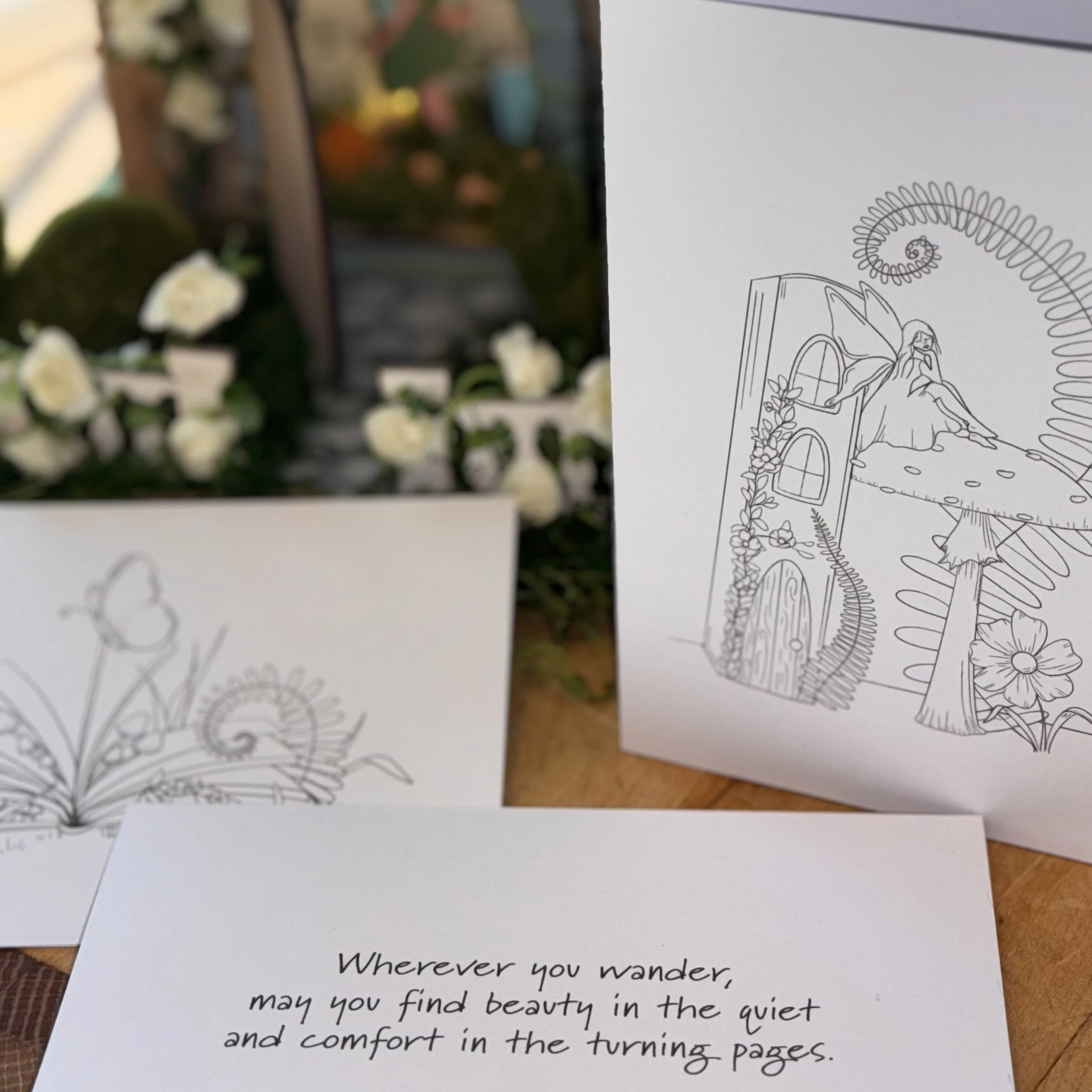 Colorful flower arrangement in the background with two black-and-white line drawings of fairy-themed illustrations and a note with a quote about finding beauty and comfort in turning pages.