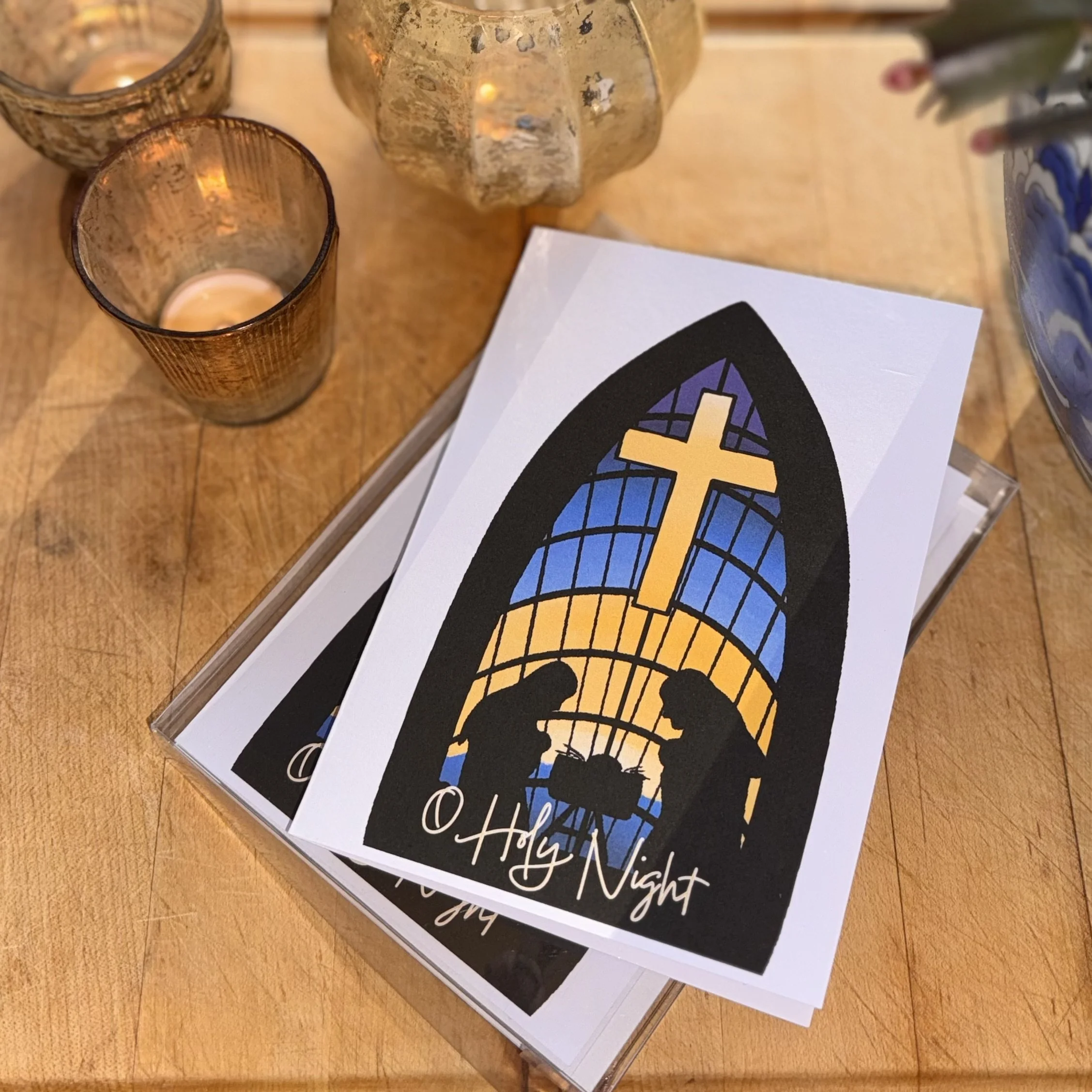 stained glass window christmas card laying flat next to candles