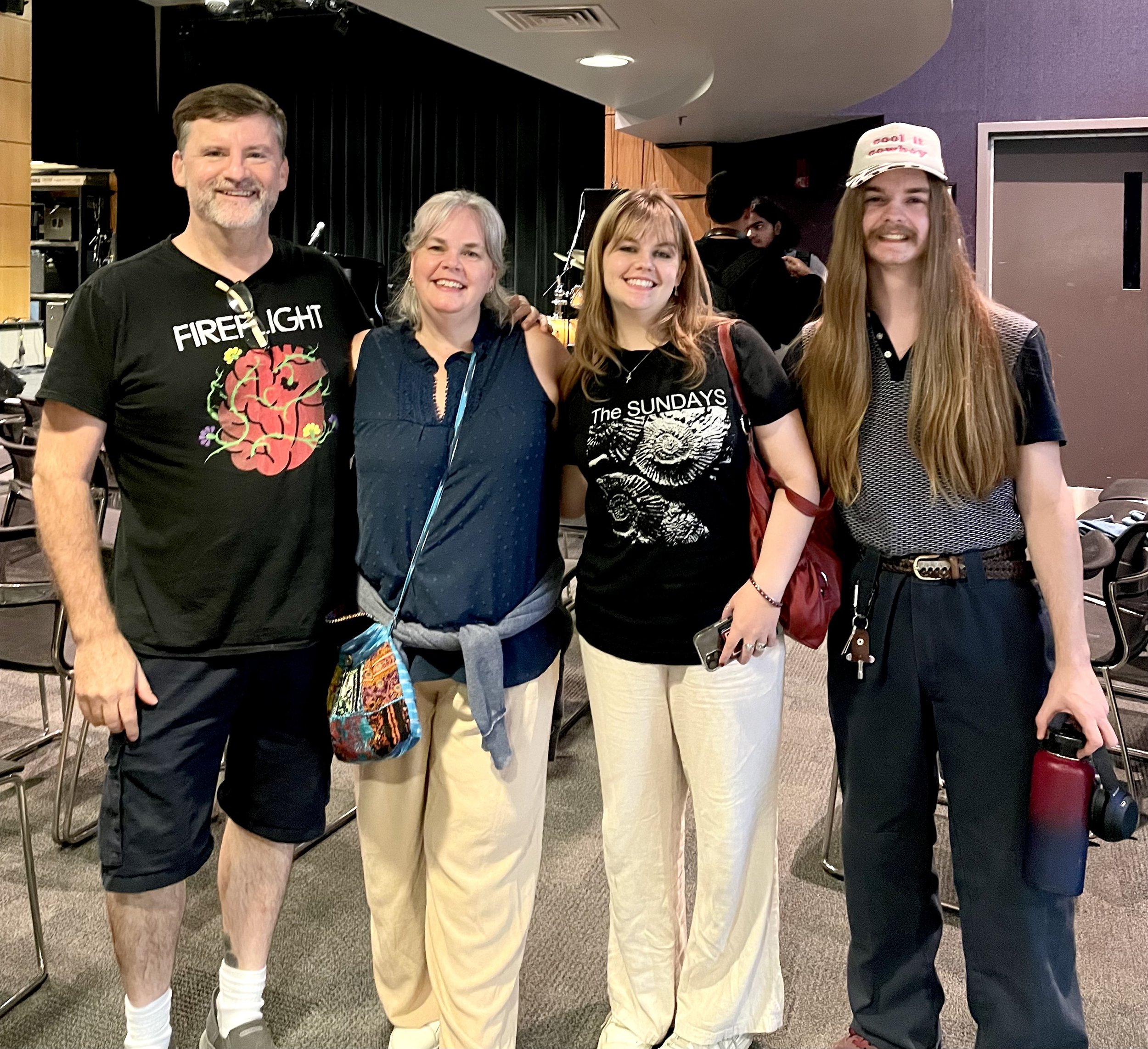 a family with arms over each other shoulders - husband, wife, daughter, son