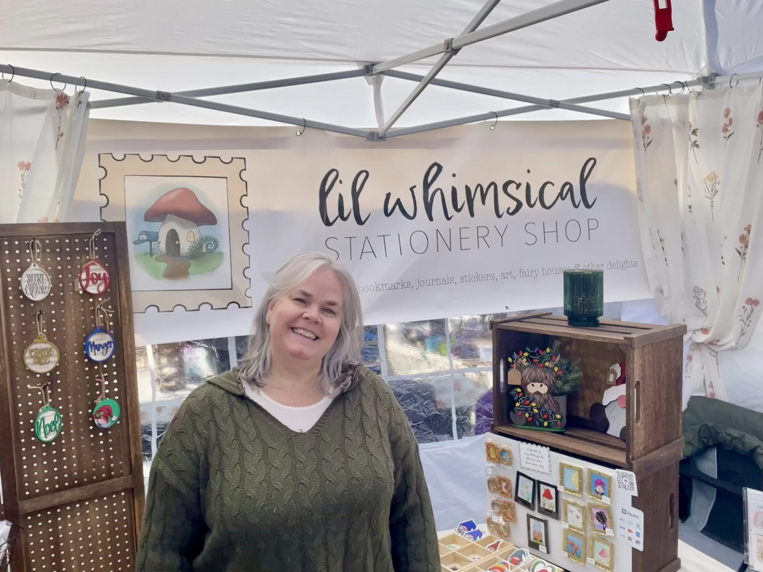 Woman in green sweater smiling standing in a market booth