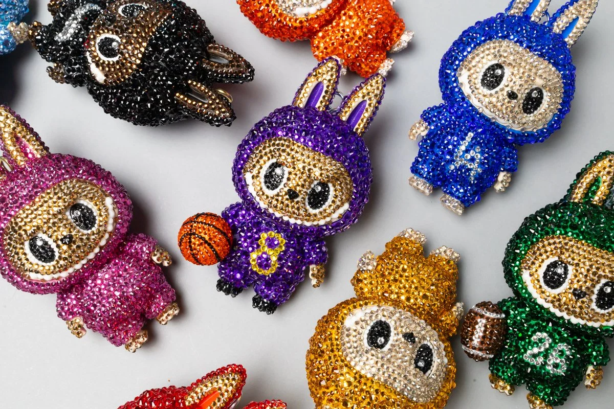 Colorful beaded character keychains, including animals and cartoon-like figures, arranged on a white surface.