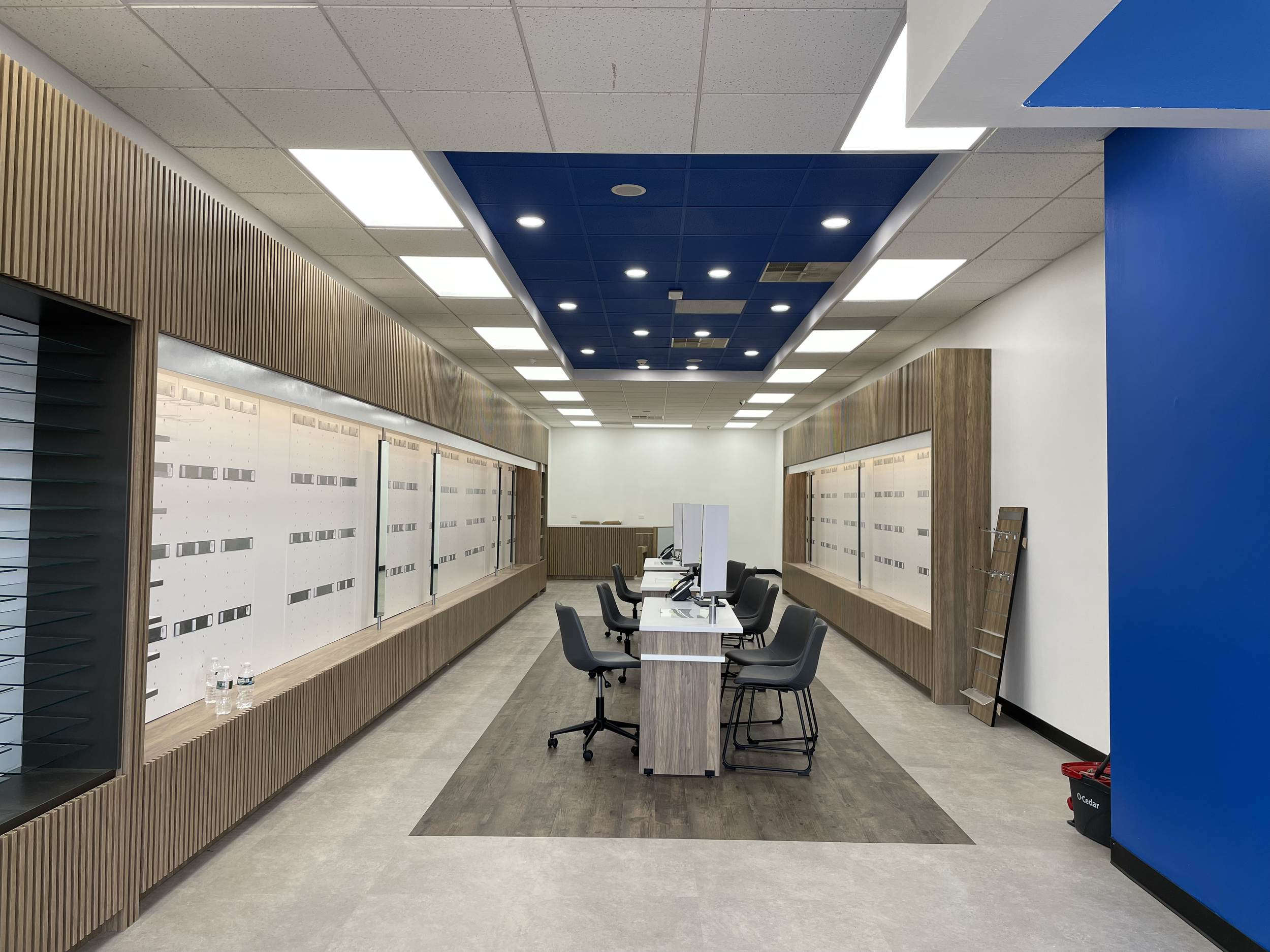 Empty admin office with desks, computers, chairs, and display boards, modern design with wood and blue accents.