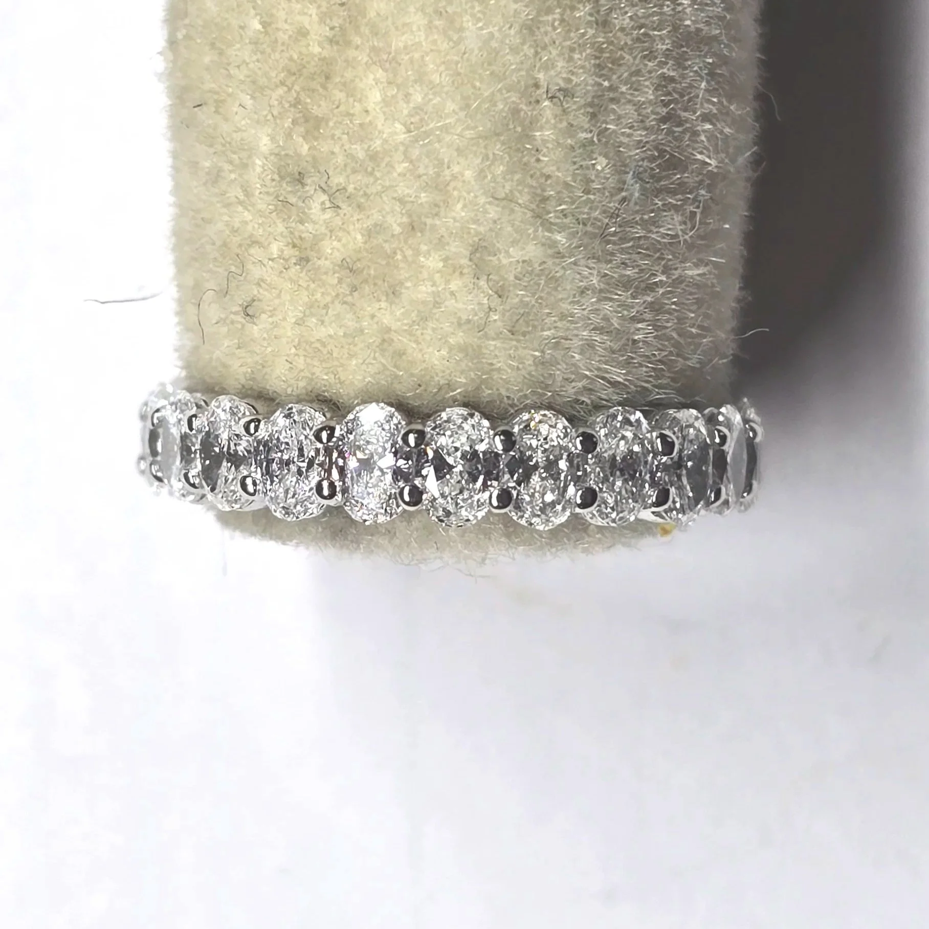 A white gold eternity band with multiple small diamonds set around it.