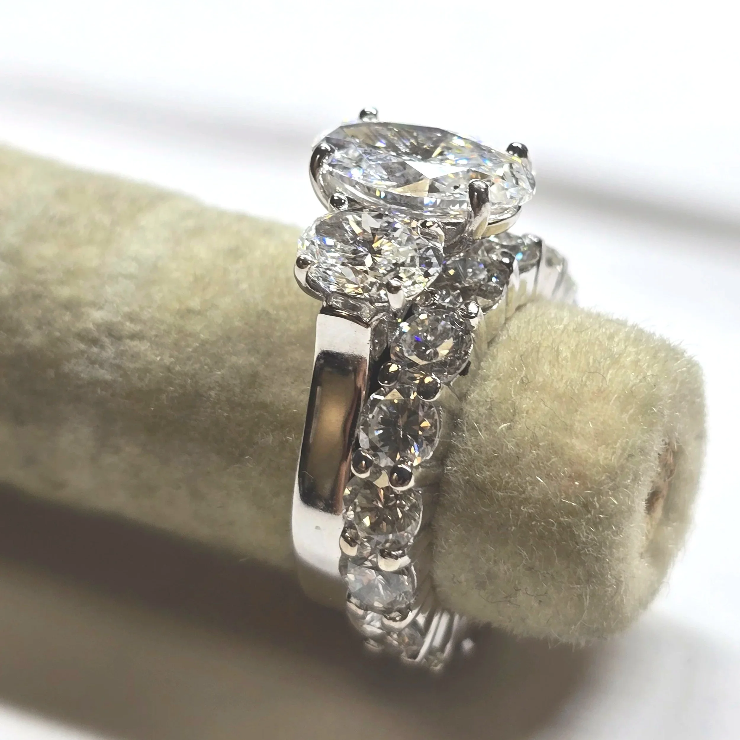 Close-up of a white gold diamond wedding ring set with an engagement ring with large oval diamond center and 2 round radiant cut diamonds and eternity band wedding ring.