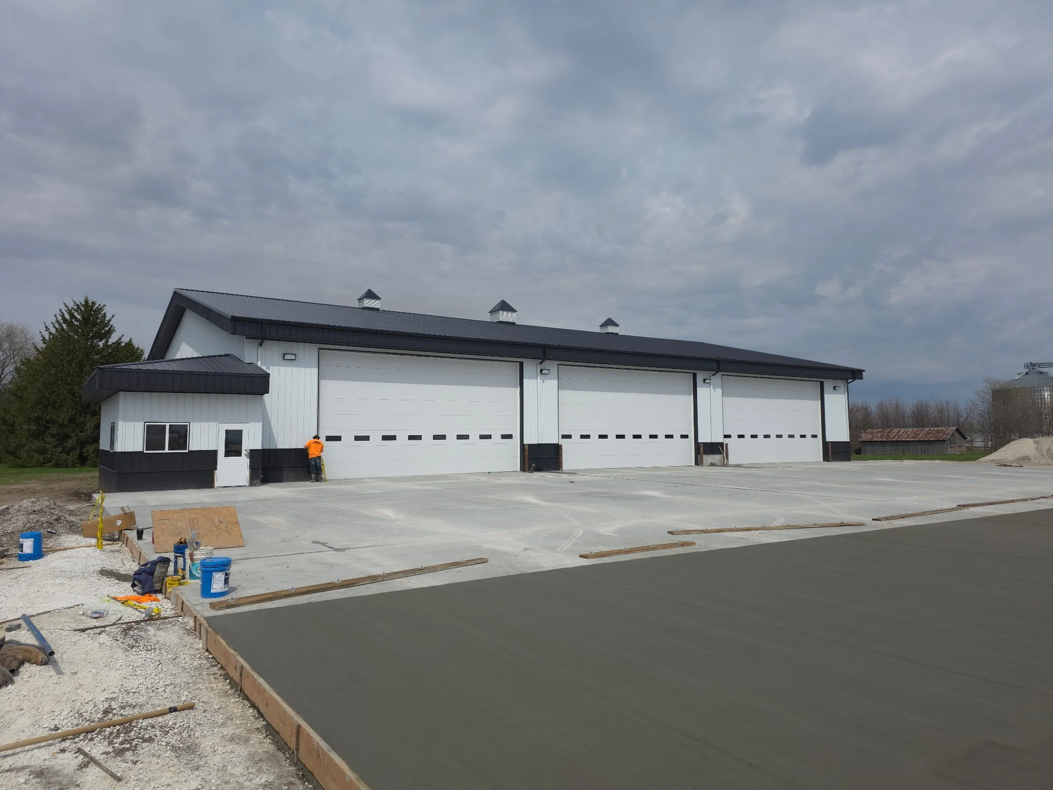 Construction site with a building under construction, workers, and fresh concrete pavement.