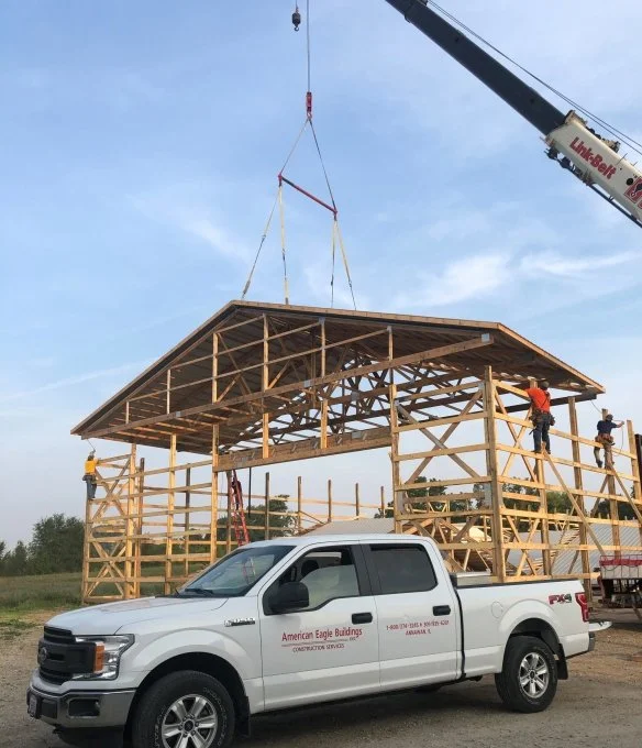 Crane lifting trusses onto building frame
