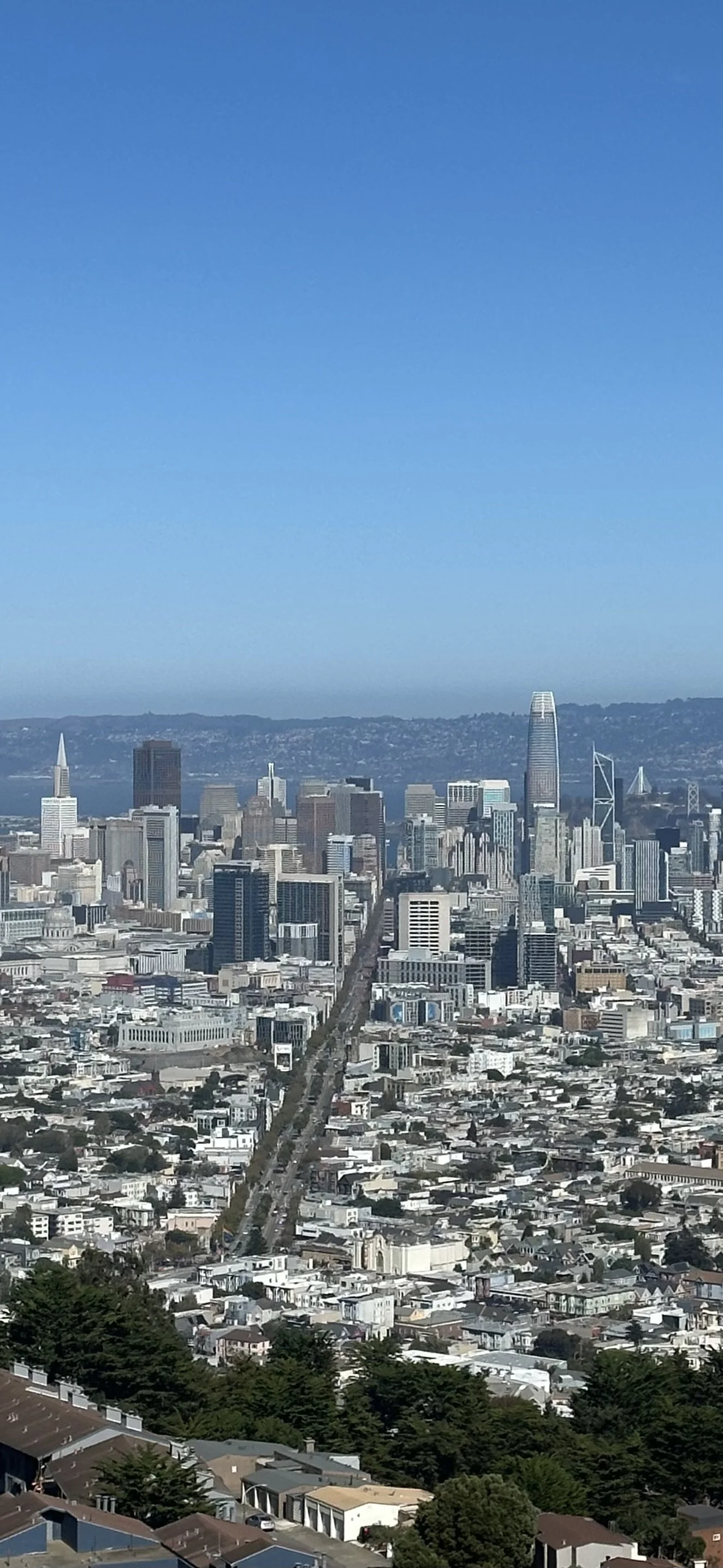 Aerial view of San Francisco skyline with downtown buildings, including Salesforce Tower, under a clear blue sky.