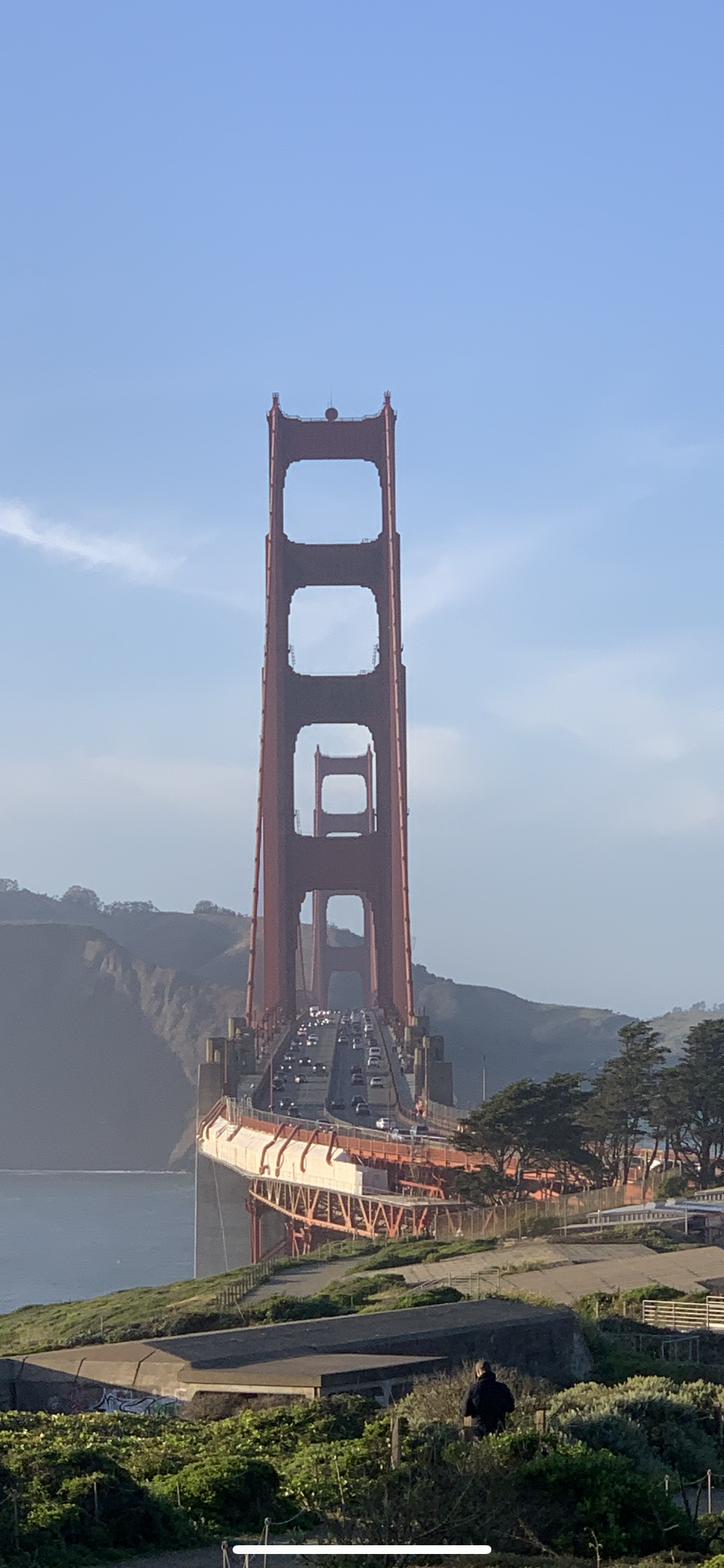 The Golden Gate Bridge in San Francisco, California, with cars crossing the span on a clear day, with hills and greenery in the background.