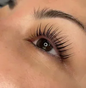 Close-up of a person's eye with long, curled eyelashes and well-groomed eyebrow.