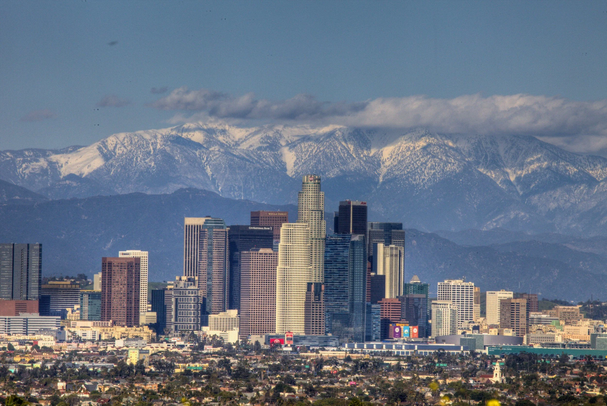 Los Angeles skyline with tall skyscrapers and snow-covered mountains in the background.