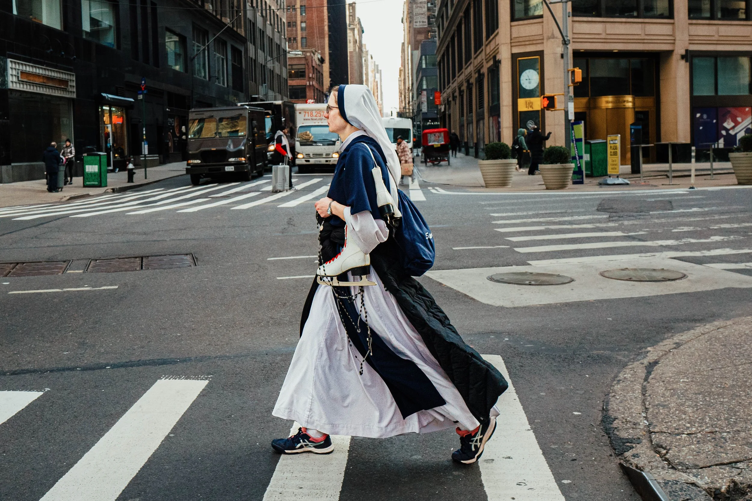 Mujer vestida con ropa religiosa y deportiva cruzando la calle en una ciudad.