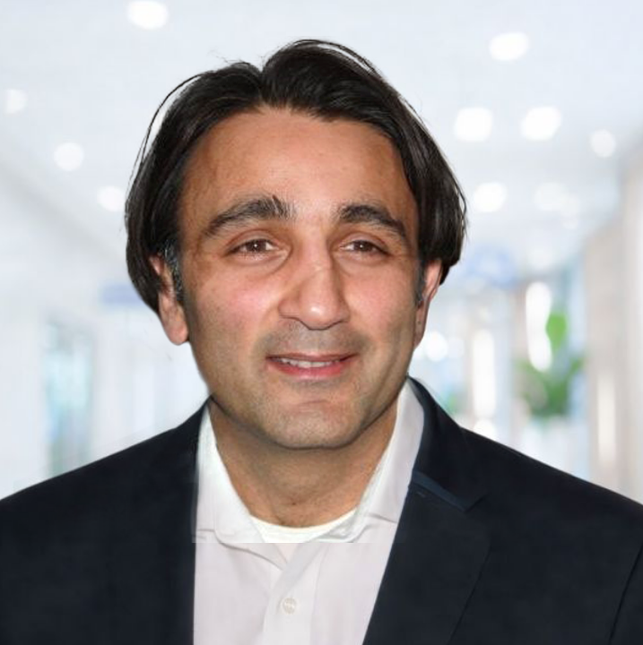 A professional of Ajay Duggal MBChB, MRCP,DPM Interim Chief Medical Officer at Caldera Therapeutics with dark hair, wearing a white shirt and dark blazer, smiling in a modern indoor setting.