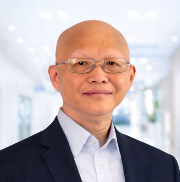 A Professional portrait of Zhong Liu, PhD Chief Technology Officer of Caldera Therapeutics with glasses wearing a dark suit jacket and a white dress shirt standing in a modern, brightly lit corridor.