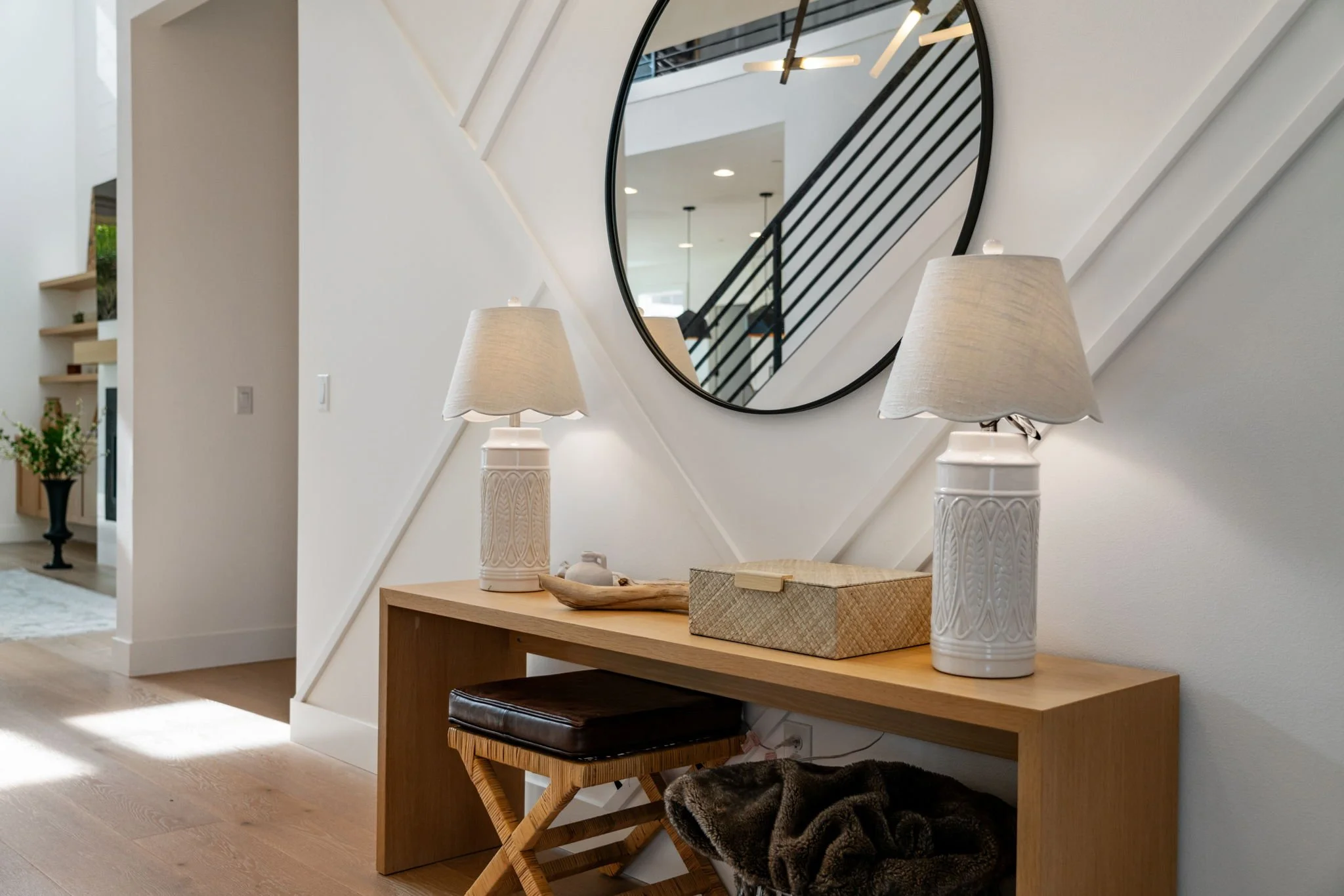 Entryway console table with two matching white table lamps, a mirror, a decorative box, and a tray, in a modern interior.