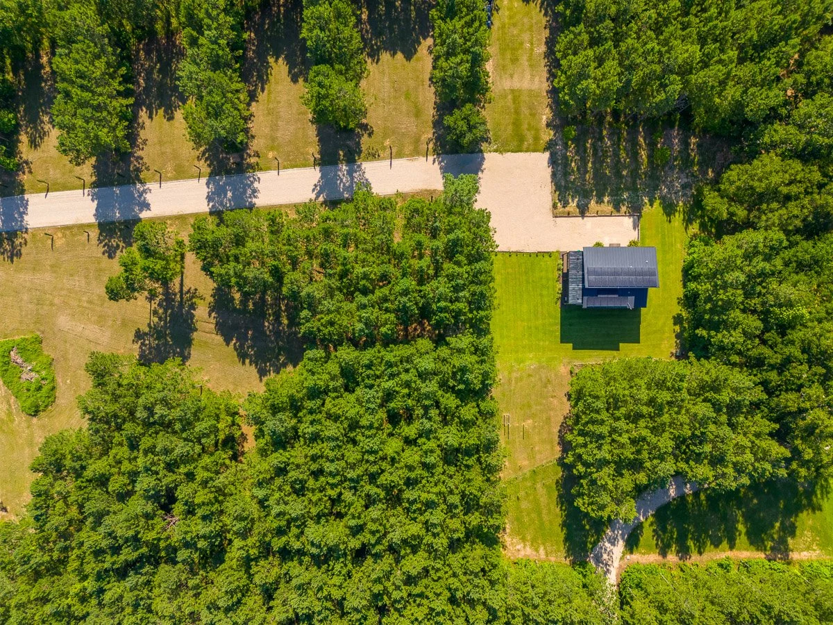 Aerial Real Estate photo of an ultra modern home on a large tract of land, surrounded by trees.