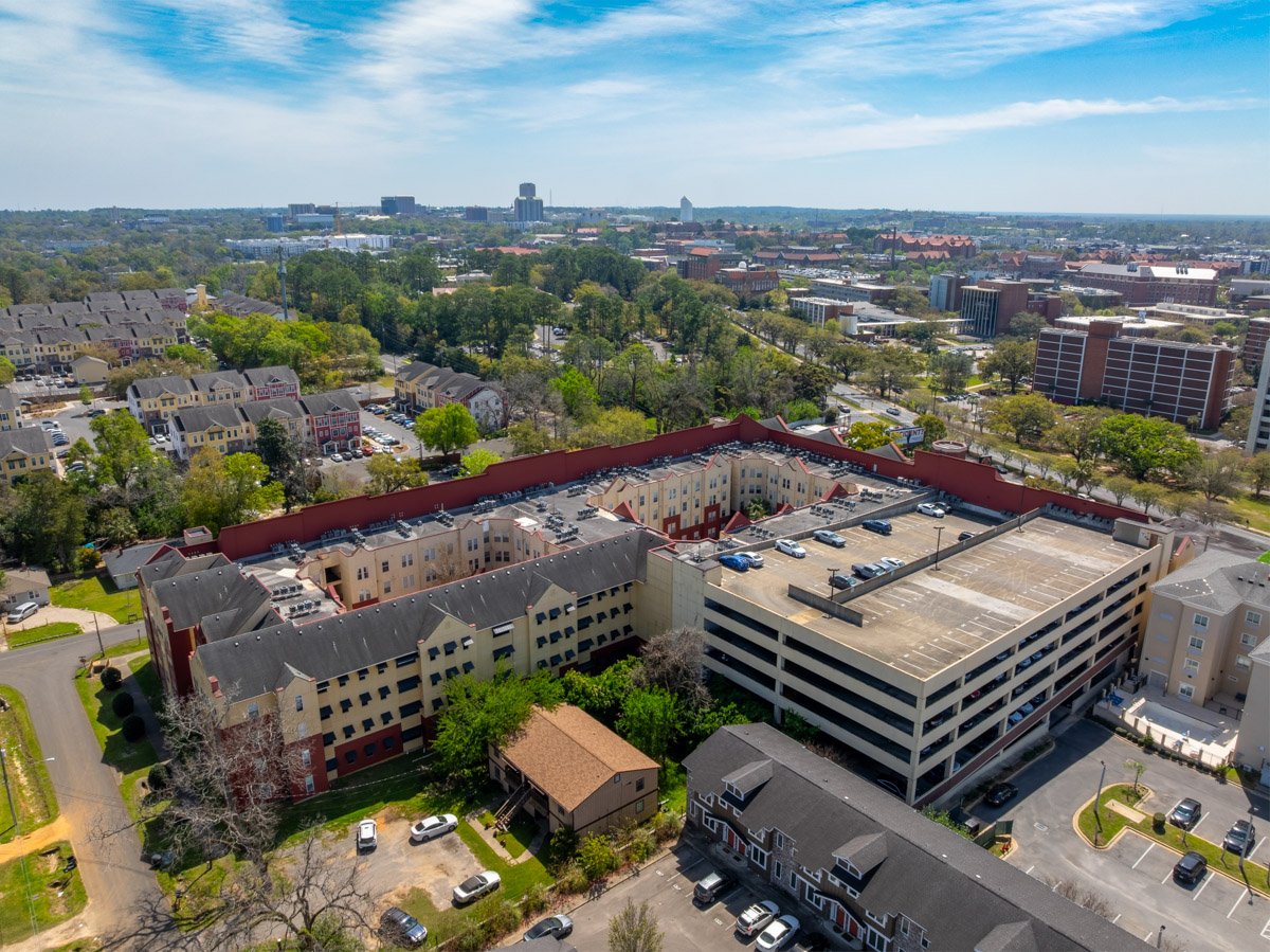 Aerial commercial Real Estate photo of a large apartment complex with university and downtown visible in the background.