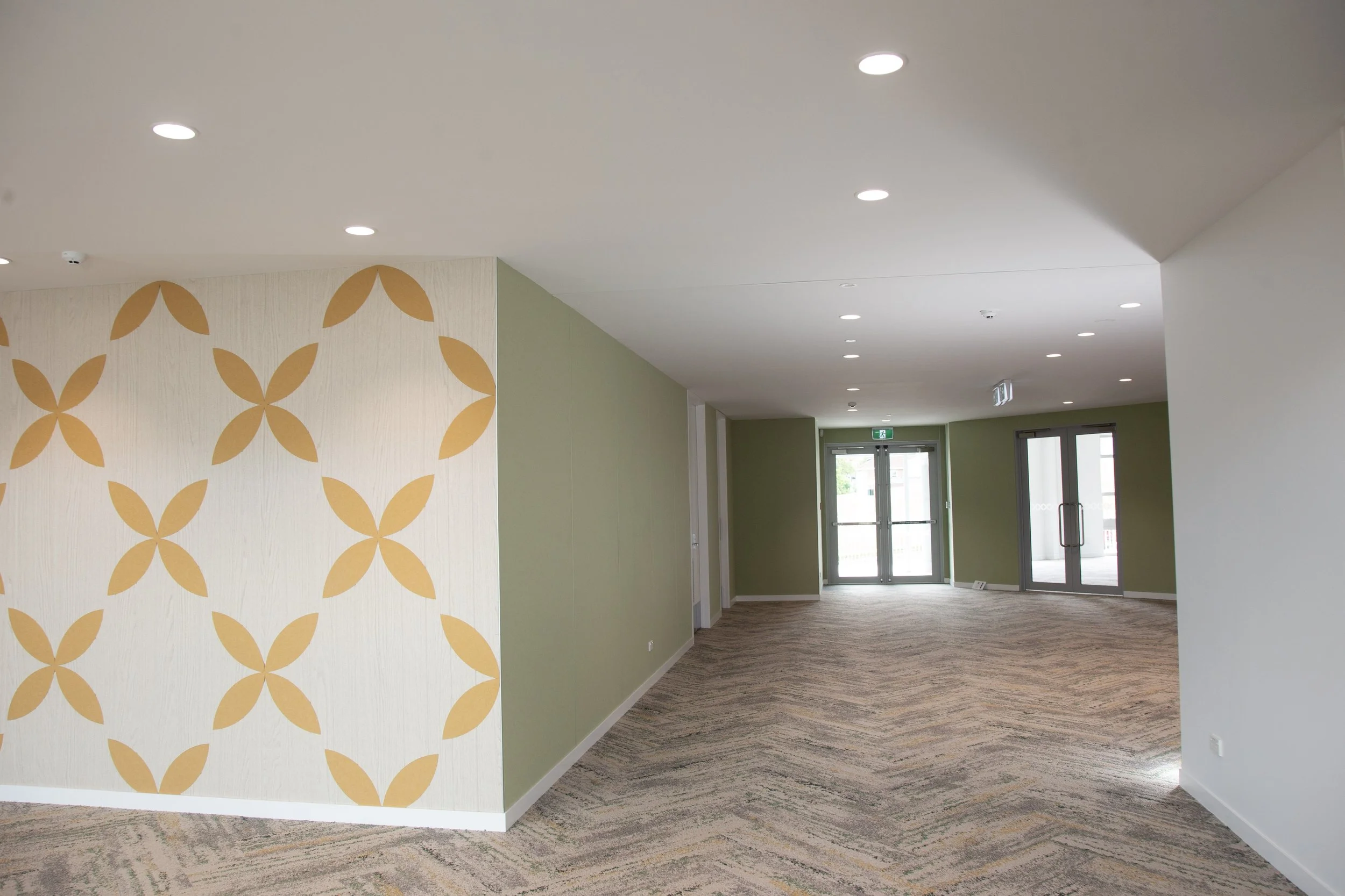 West-Auckland commercial interior space with patterned carpet, green walls, and glass doors at the end.