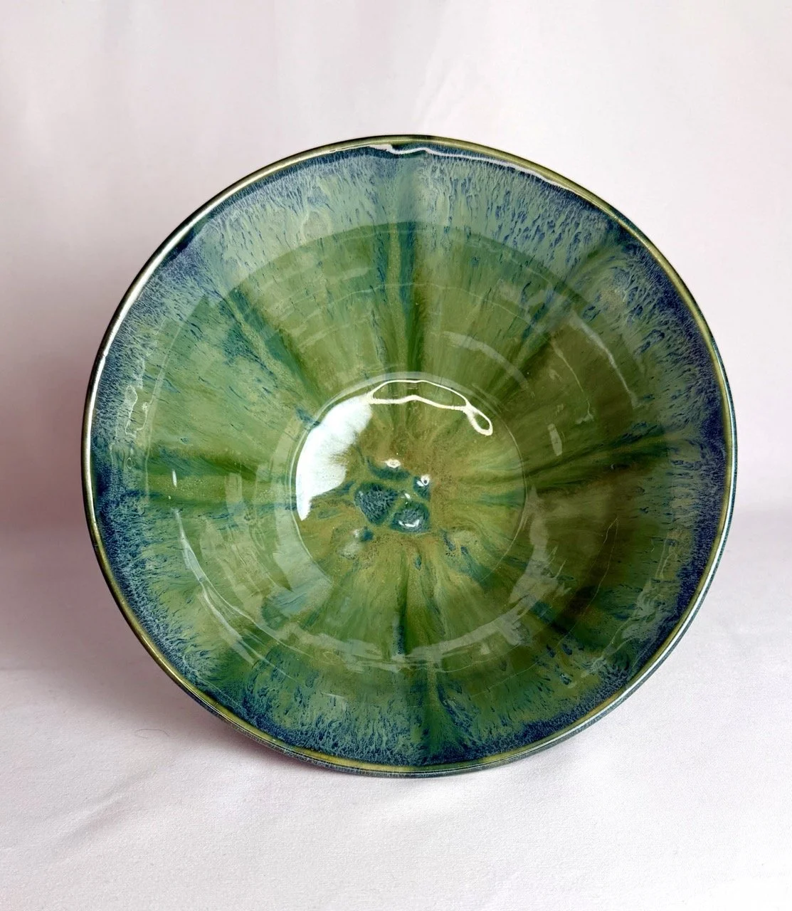 A decorative ceramic bowl with a green and blue glaze pattern.