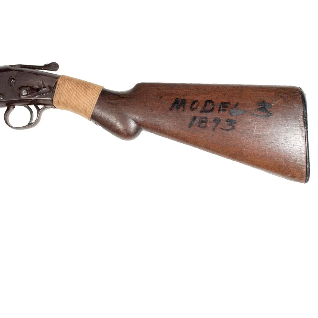 Part of a vintage rifle with a wooden stock labeled 'MODEL 3 1973' in black ink.