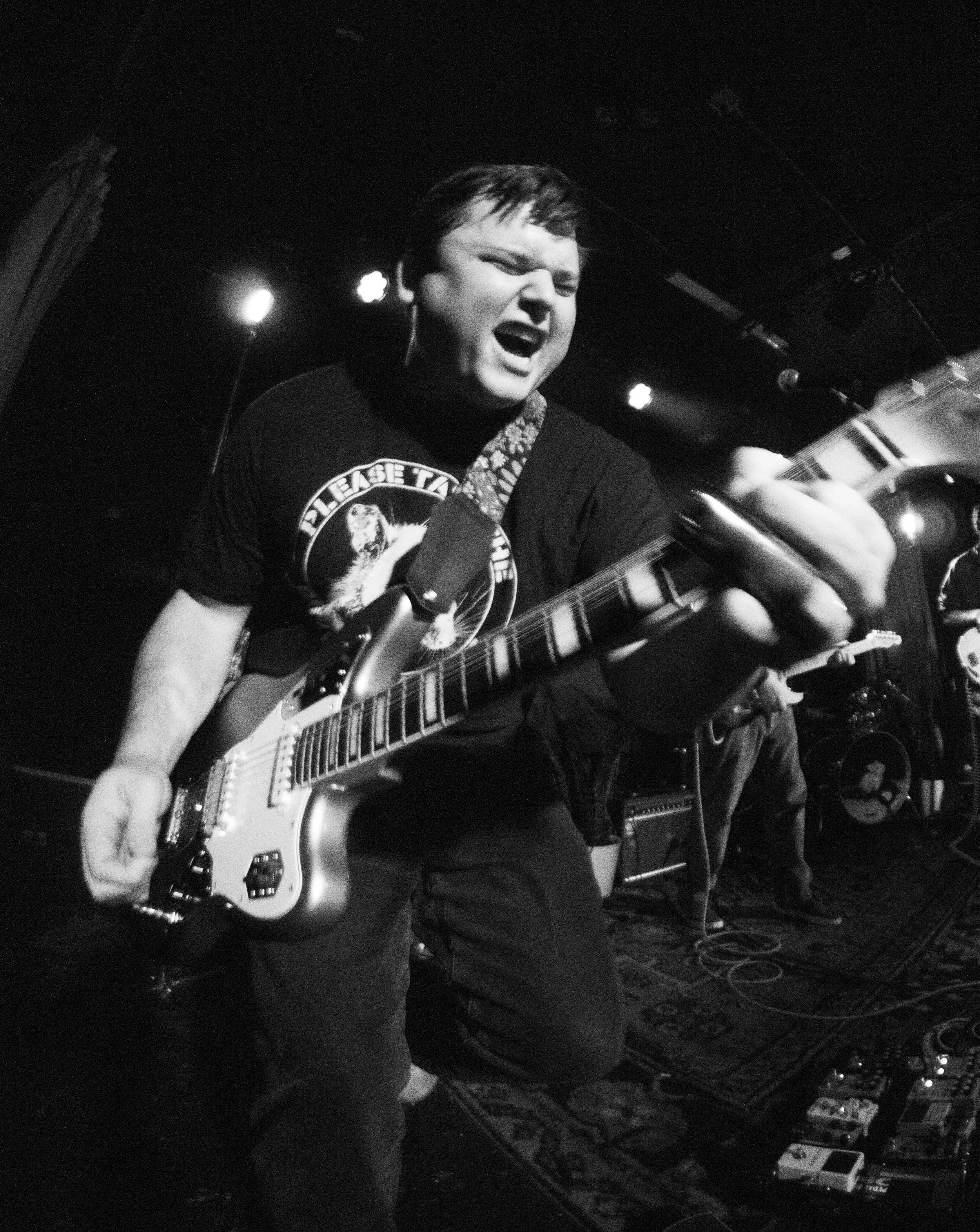 A young man passionatelyPlaying an electric guitar on stage during a live music performance.