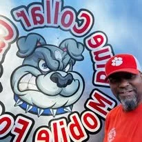 Person in red hat taking a selfie in front of a large circular sign with a cartoon bulldog and text.
