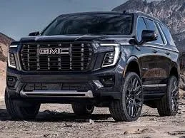 Black GMC SUV parked on rocky terrain with mountains in the background.