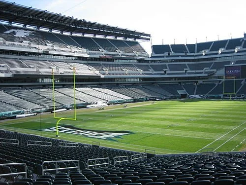 Empty football field in a large stadium with goalposts and seating areas.