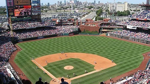 A baseball stadium filled with spectators, with players on the field practicing or preparing for a game.