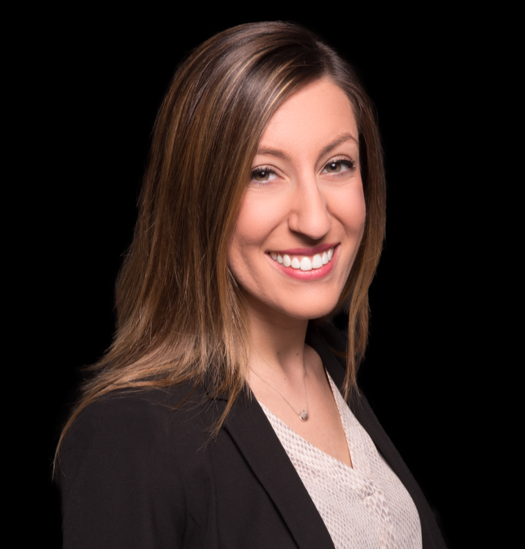 A woman with shoulder-length light brown hair, wearing a black blazer over a light-colored top, smiling at the camera against a black background.