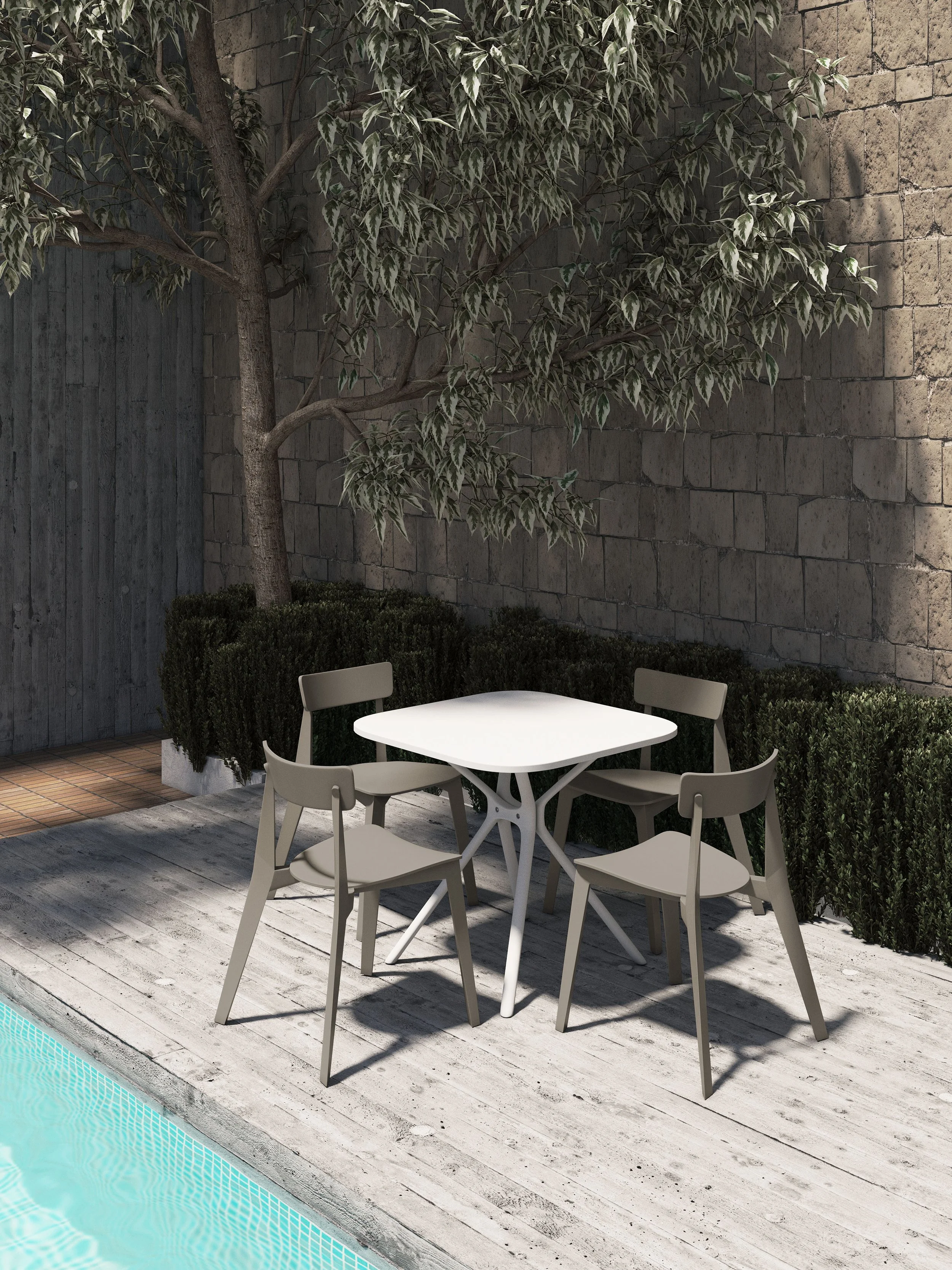 Mesa blanca con cuatro sillas en un patio junto a una piscina, rodeada de arbustos y un árbol junto a una pared de ladrillos.