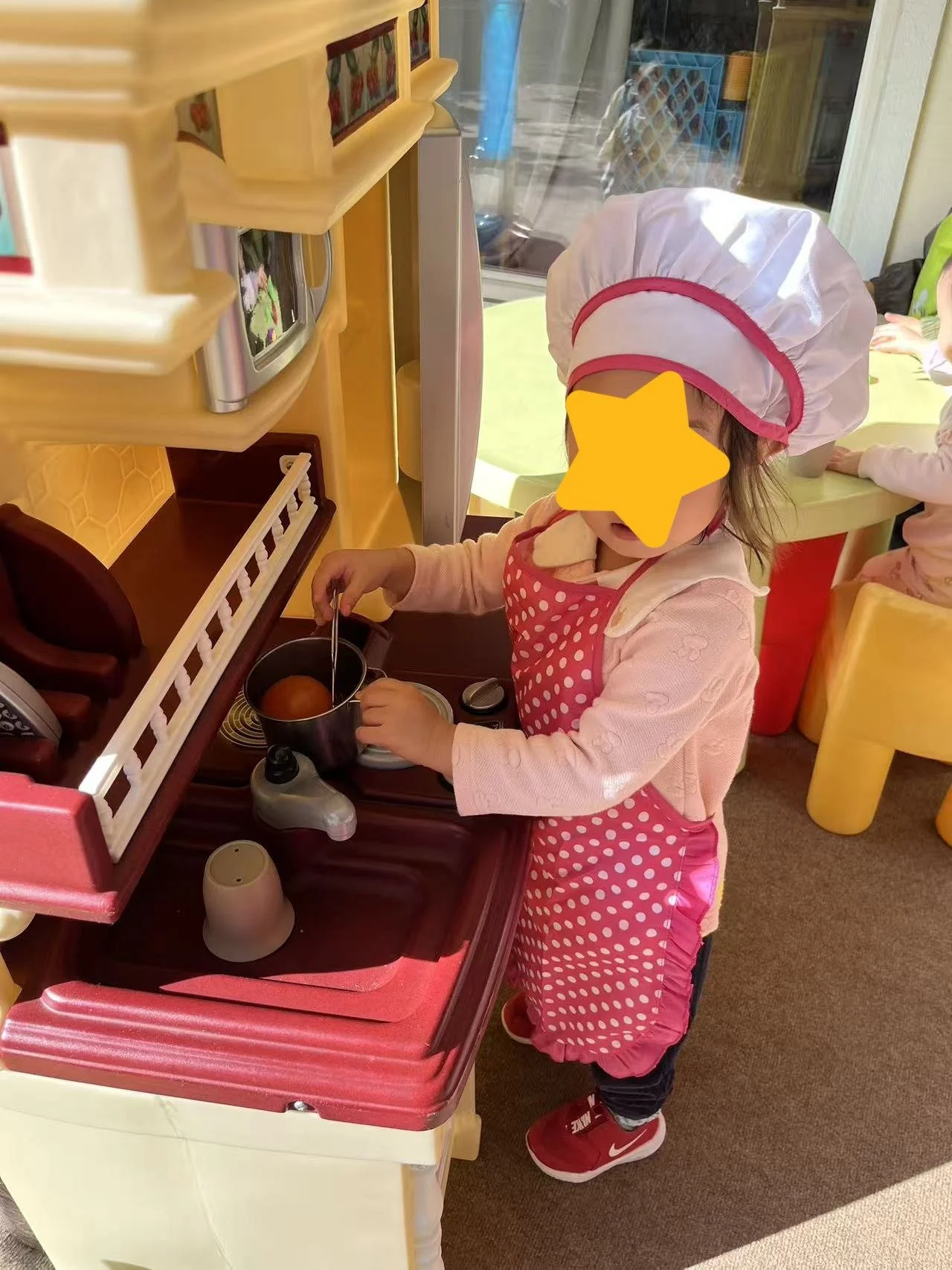 Child engaging in pretend play at Red Apple Daycare, using a toy kitchen to support creativity and social development.
