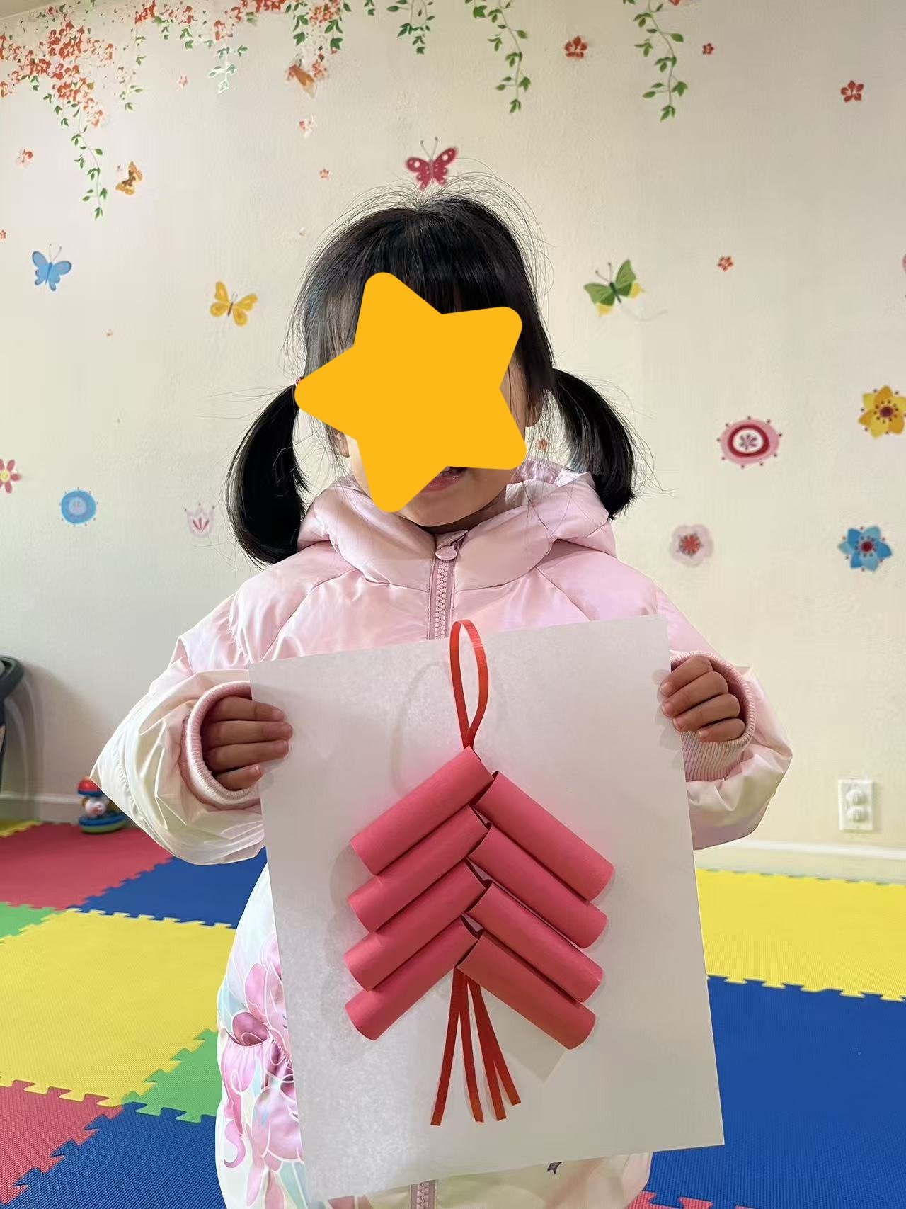 Child sharing a completed craft project at Red Apple Daycare, building confidence and creativity through art activities.
