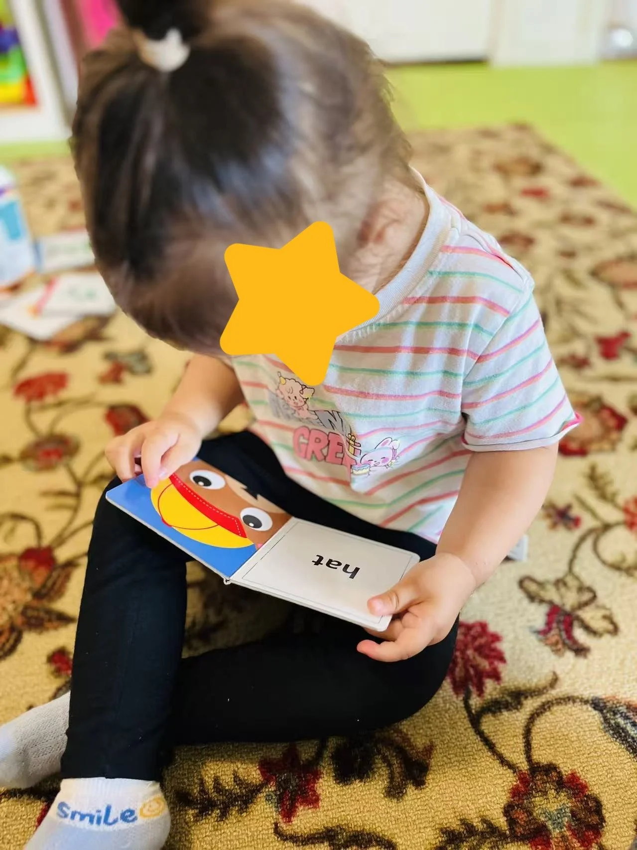 Toddler learning vocabulary with flash cards during early language activities at Red Apple Daycare in Santa Clara.