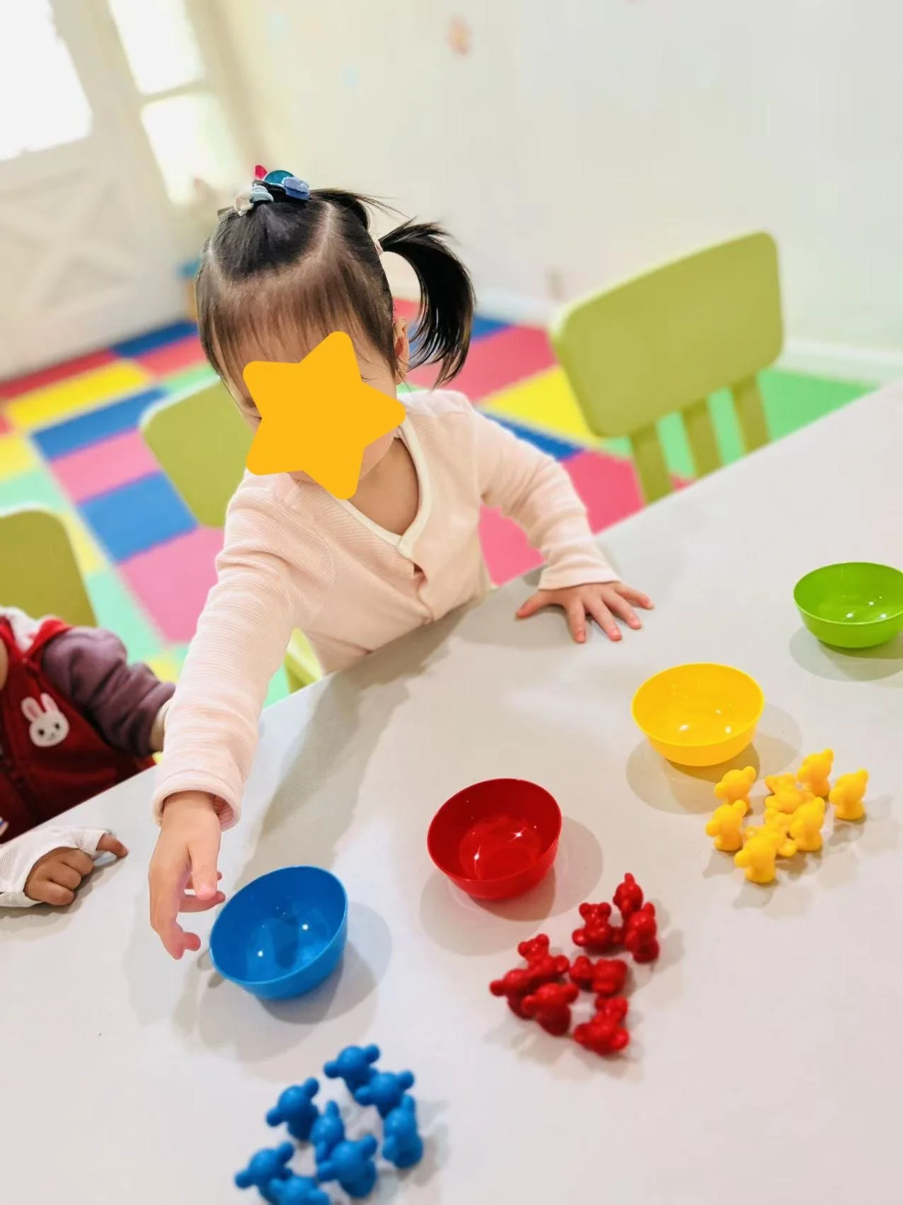 Child engaging in tabletop play at Red Apple Daycare, developing fine motor skills and hand-eye coordination.
